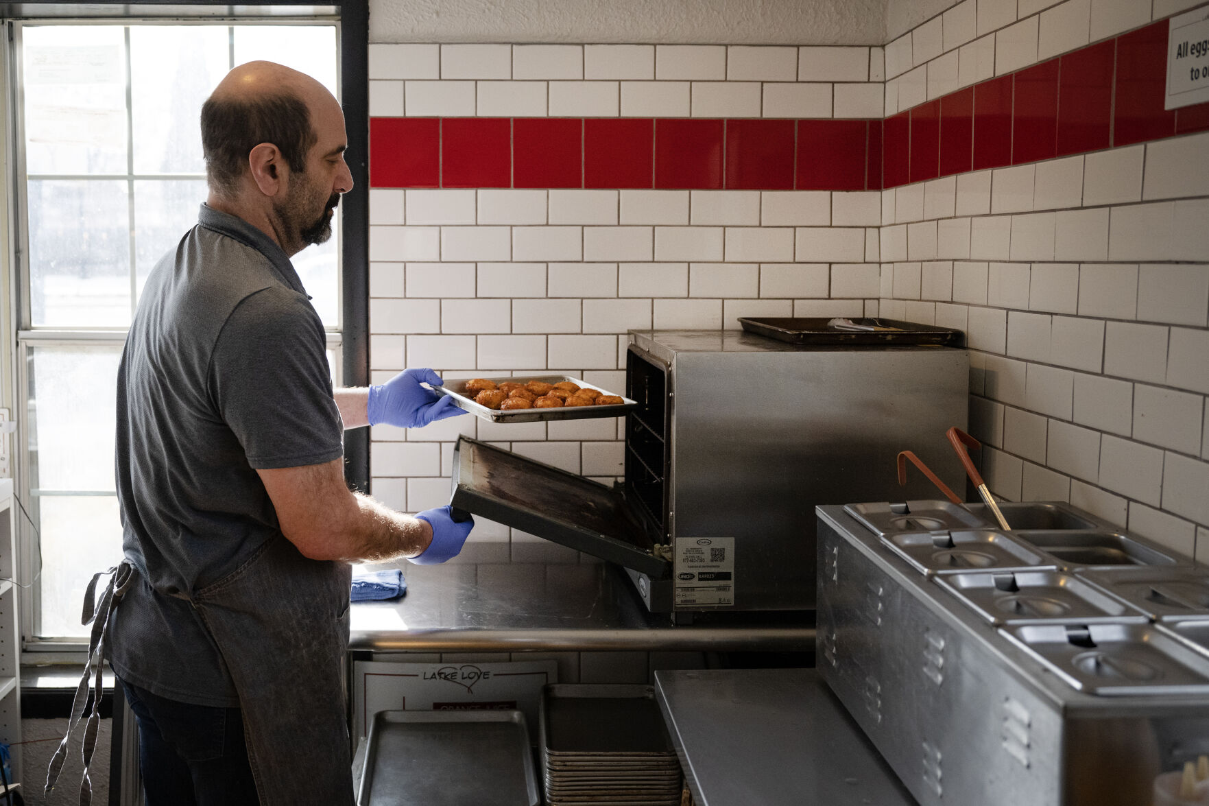 LEFT: Steve Shander puts a tray of latkes in the oven while prepping customers’ orders just after opening this month at Latke Love in Littleton. (TimHursttim.hurst@gazette.comhttps://secure.gravatar.com/avatar/aca82bd62b4ee425c598527cd6faa1b1?d=mm&r=g)