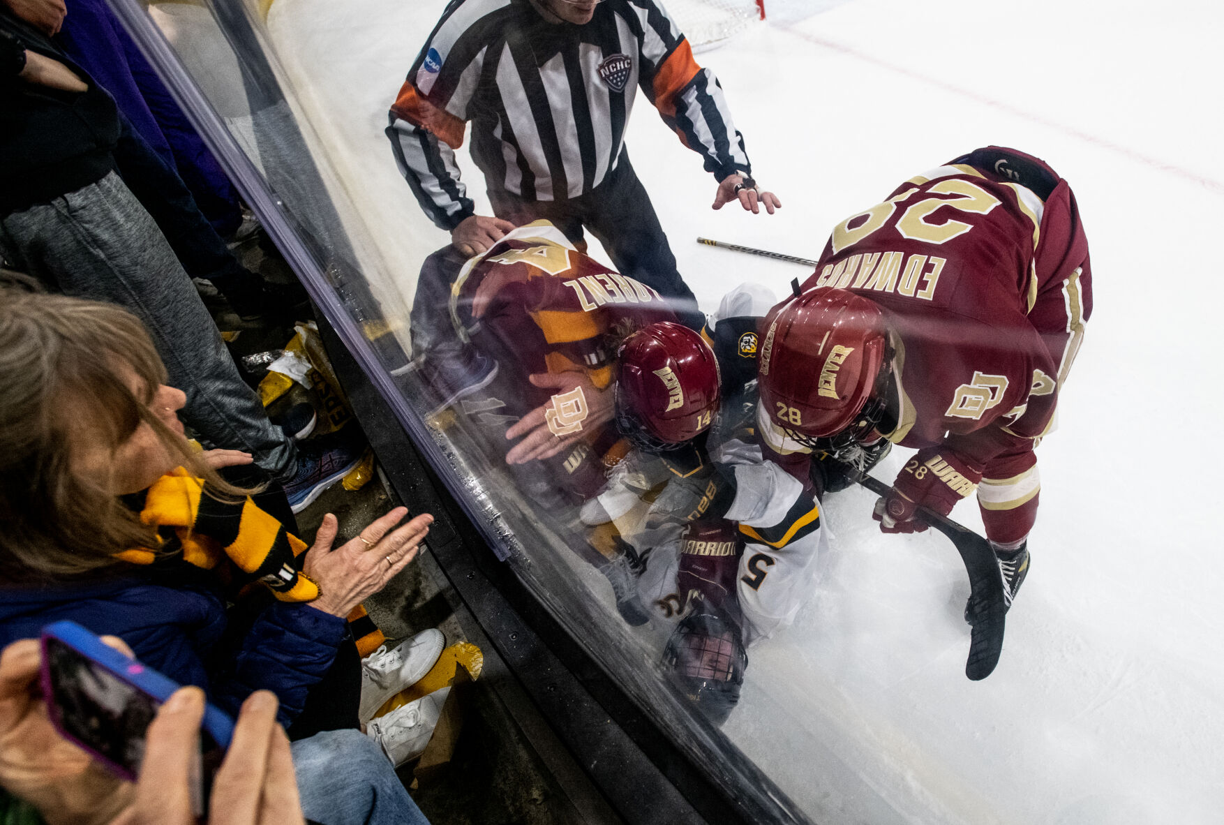Denver forward Brett Edwards (28) and Denver forward Rieger Lorenz (14) pin down Colorado College defenseman Jack Millar (5) as a referee tries to separate them and fans look on from above in the third period of a hockey game on Saturday, Feb. 4, 2023, at Ed Robson Arena in Colorado Springs, Colo. (Parker Seibold, The Gazette) (Parker Seibold)