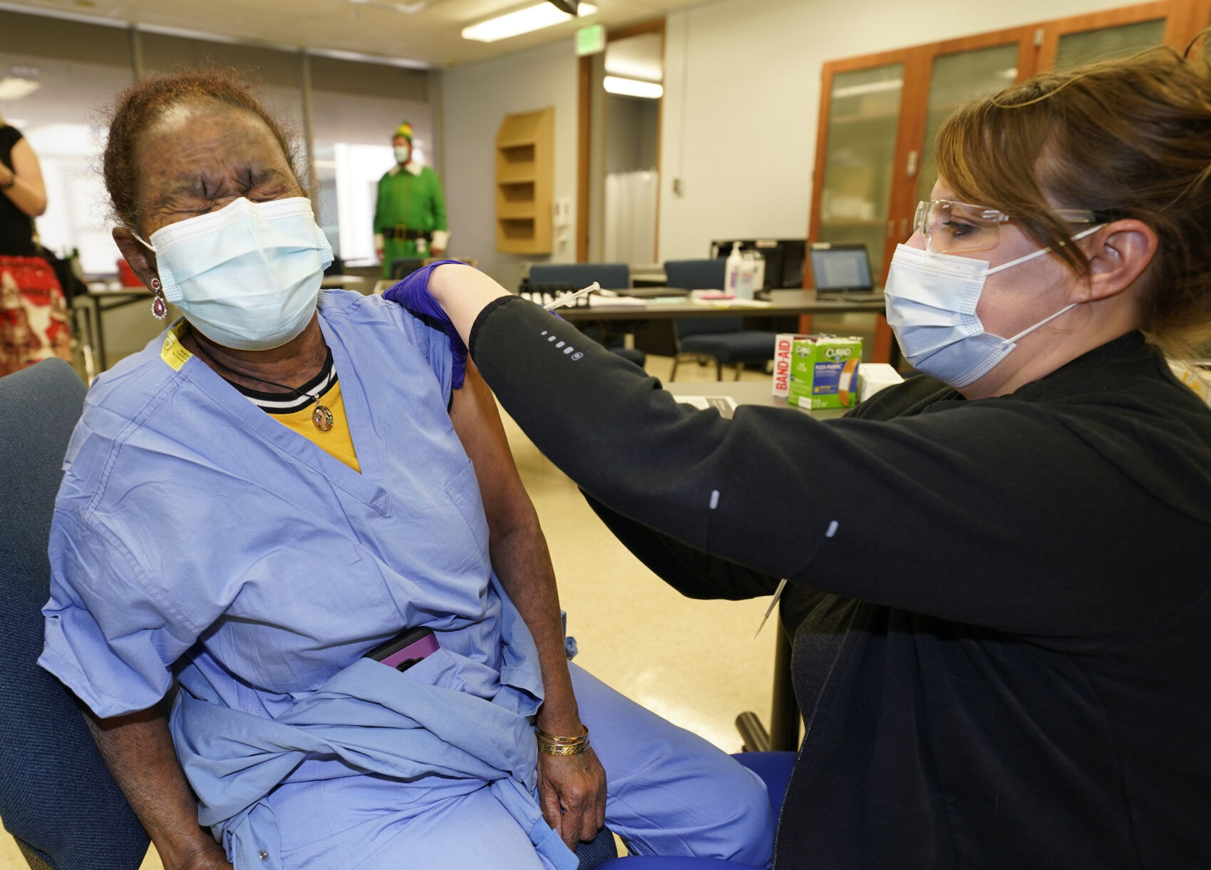 In this file photo, Rebecca Hong, right, a registered nurse who is the assistant nurse manager in the mom/baby unit at Rose Medical Center, administers the COVID-19 vaccine from Moderna to hospital worker Kudusan Tekle in the first round of staff vacinations at Rose with the Moderna product on Dec. 23, 2020, in Denver. ((AP Photo/David Zalubowski))