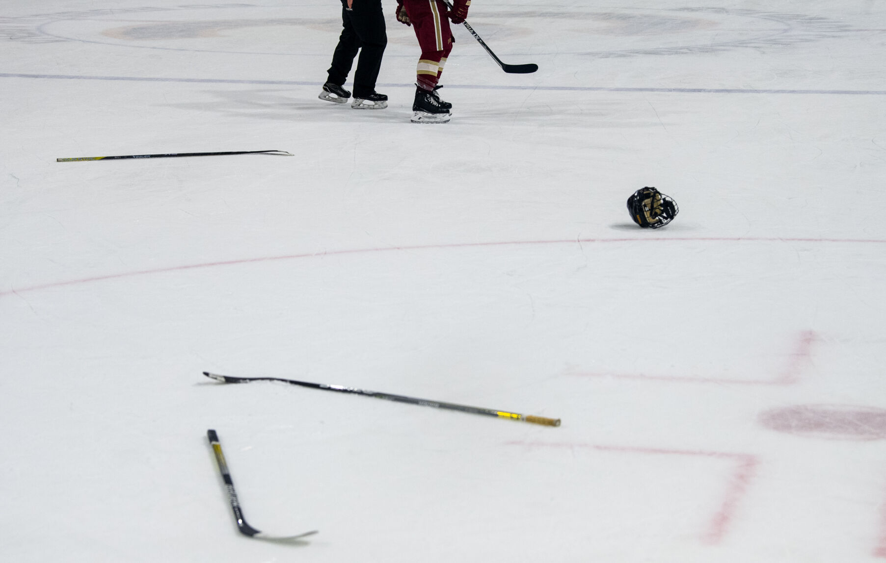 Sticks and a helmet lay scattered on the ice as a Denver University player is escorted to the penalty box after a brawl broke out between DU and Colorado College players in the third period of a hockey game on Saturday, Feb. 4, 2023, at Ed Robson Arena in Colorado Springs, Colo. (Parker Seibold, The Gazette) (Parker Seibold)