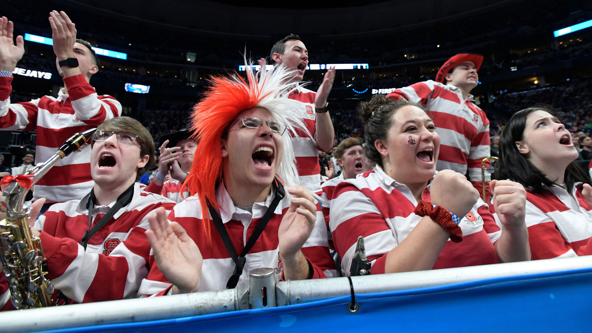 Andrew Otelsberg, center with wig, Sarah Sisk, second from right, Katie Phillips, right, and the rest of the North Carolina State Pep Band cheer for their Wolfpack during the second half of a first round of the Men’s NCAA Tournament Friday, March 17, 2023, against the Creighton Bluejays at Ball Arena in Denver. (The Denver Gazette, Christian Murdock) (ChristianMurdockchristian.murdock@gazette.comhttps://secure.gravatar.com/avatar/7b418fa9a684d03a433f79e3e5065029?d=mm&r=g)