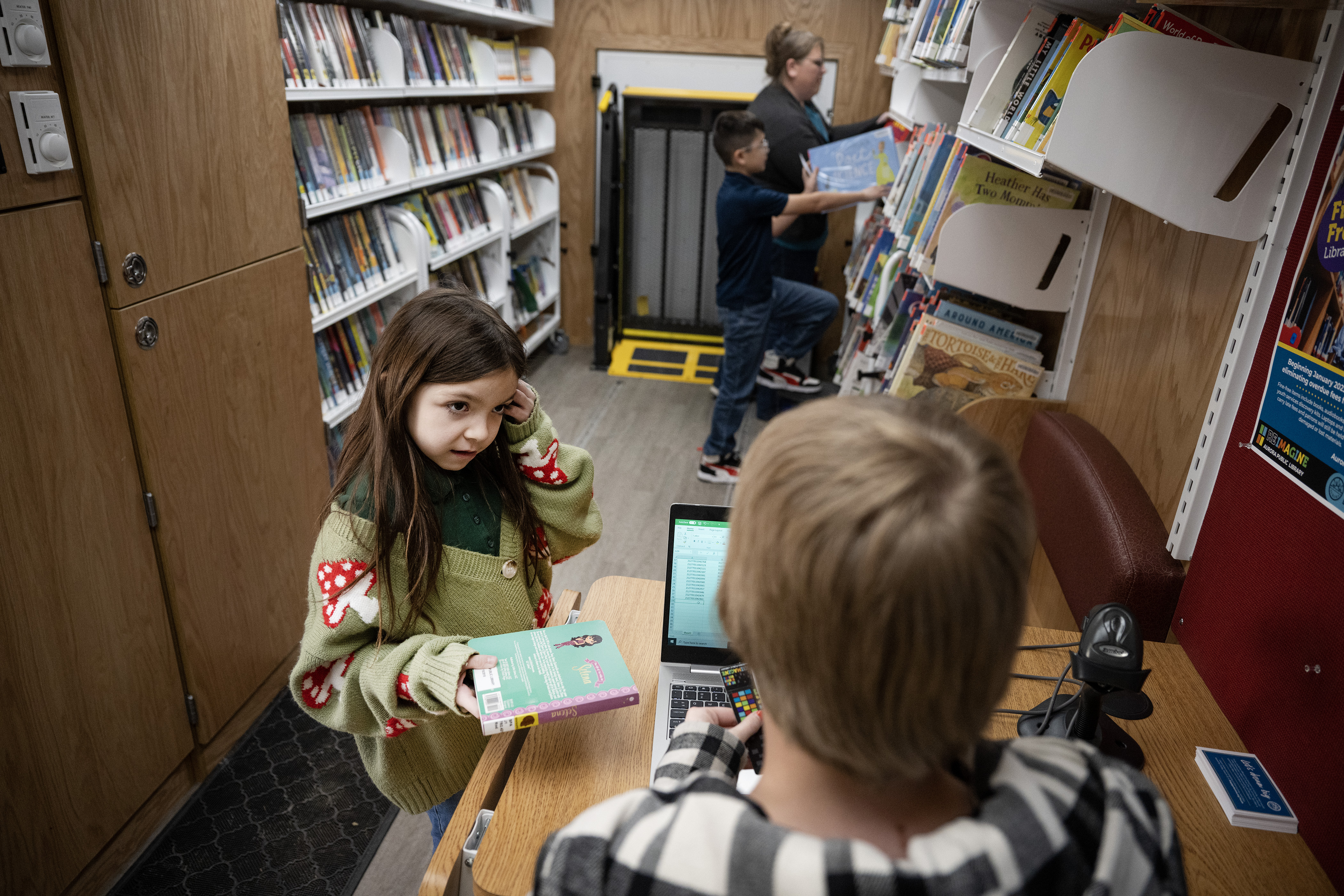 Third grader Ilianah Bronson checks out a copy of “The Life of - La Vida De Selena,” by Patty Rodriguez and Ariana Stein, from programming librarian Stacy Hirschhorn on Aurora Public Library’s Bookmobile on Tuesday, Feb. 28, 2023, at High Point Academy in Aurora, Colo. (Timothy Hurst/Denver Gazette) (TimHursttim.hurst@gazette.comhttps://secure.gravatar.com/avatar/aca82bd62b4ee425c598527cd6faa1b1?d=mm&r=g)