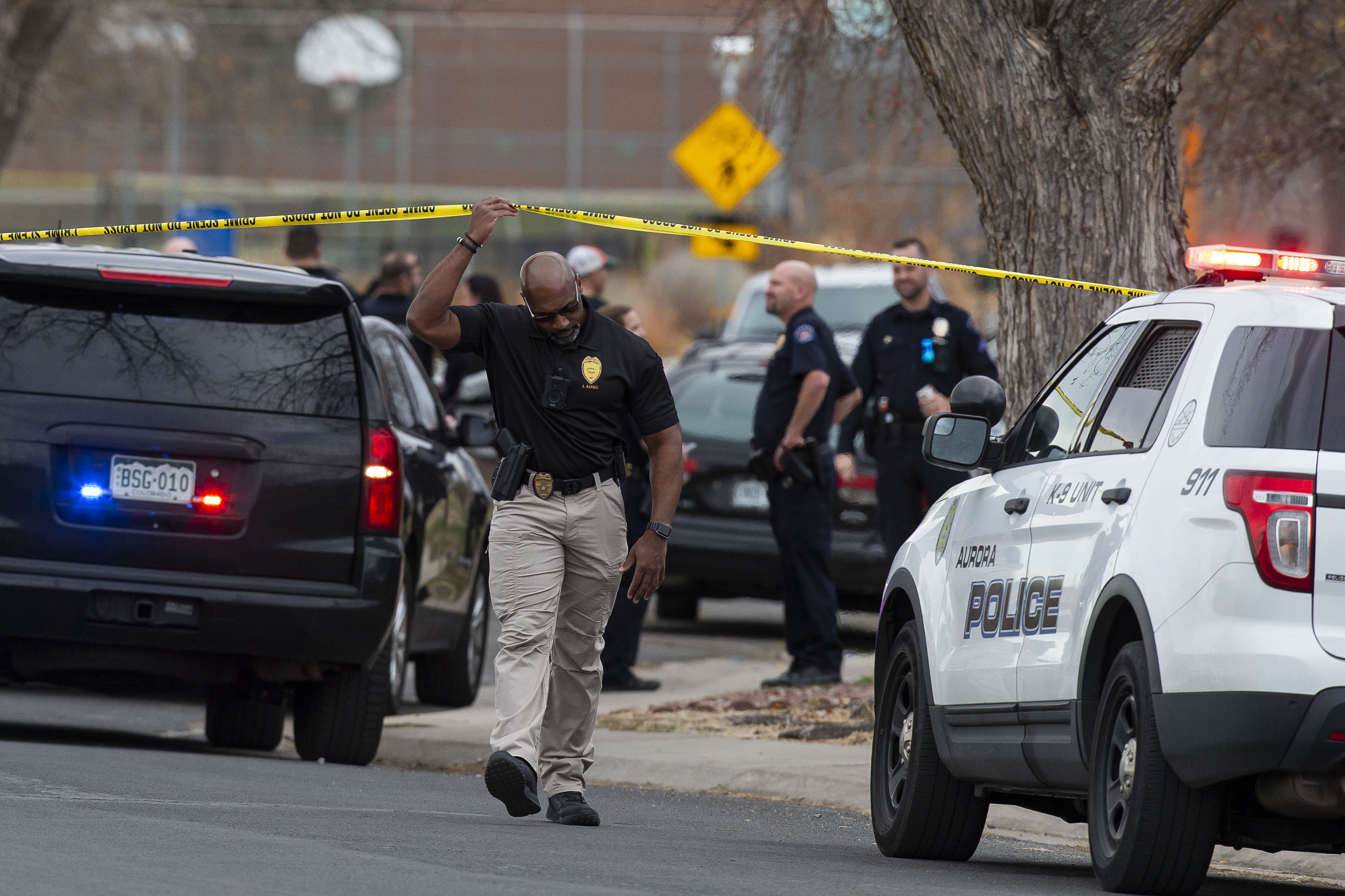 In this file photo, an investigator walks under crime scene tape at the scene of a shooting at Nome Park on Monday, Nov. 15, 2021, in Aurora, Colo. Prosecutors later filed more than a dozen charges against a 16-year-old boy accused of injuring six teenagers in the shooting. (Timothy Hurst/The Gazette) (Timothy Hurst)