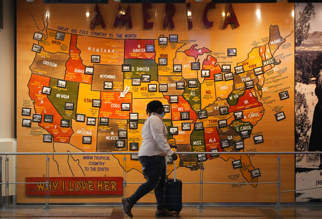 A traveler makes her way past a map of the United States at Denver International Airport in this file photo. (AP Photo/David Zalubowski) ((AP Photo/David Zalubowski))