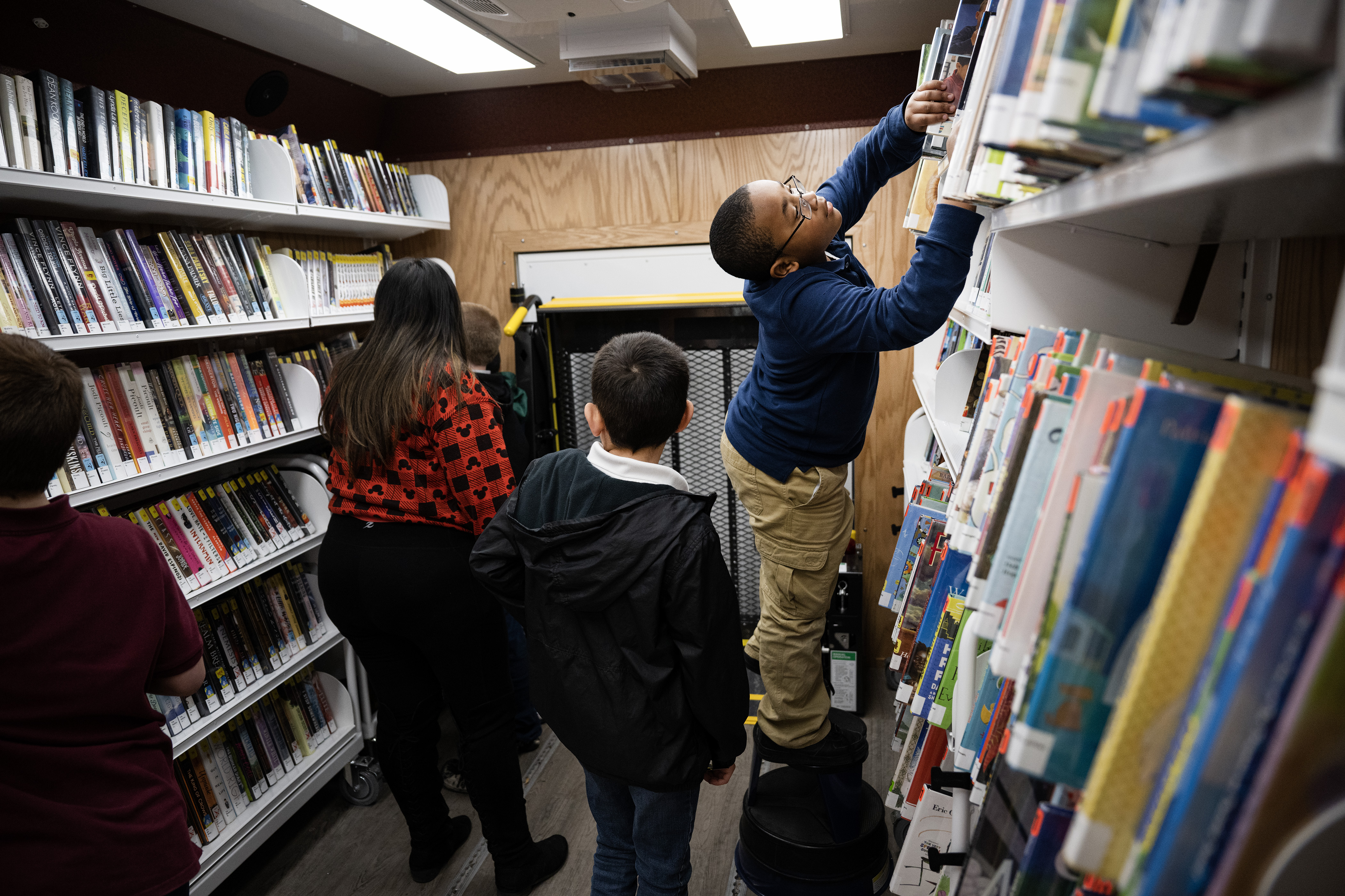 Third grader Terrence Williams stands on a stool while searching for a book to check out from Aurora Public Library’s Bookmobile on Tuesday, Feb. 28, 2023, at High Point Academy in Aurora, Colo. (Timothy Hurst/Denver Gazette) (TimHursttim.hurst@gazette.comhttps://secure.gravatar.com/avatar/aca82bd62b4ee425c598527cd6faa1b1?d=mm&r=g)