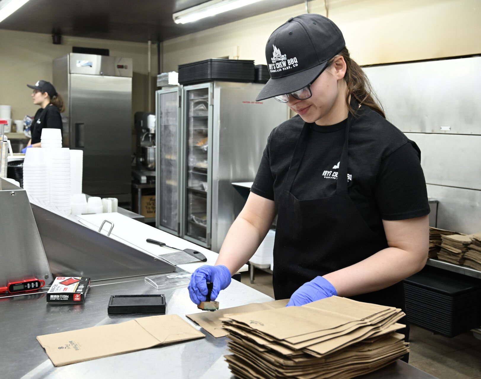 Madilynn Cassada stamps bags with the Roy’s Crew BBQ logo.
