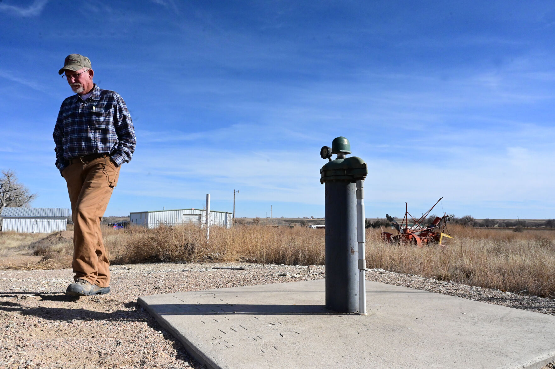 Norman Noe of the South Swink Water Co. walks past one of the wells that goes into a deep aquifer and carries radium in the water.