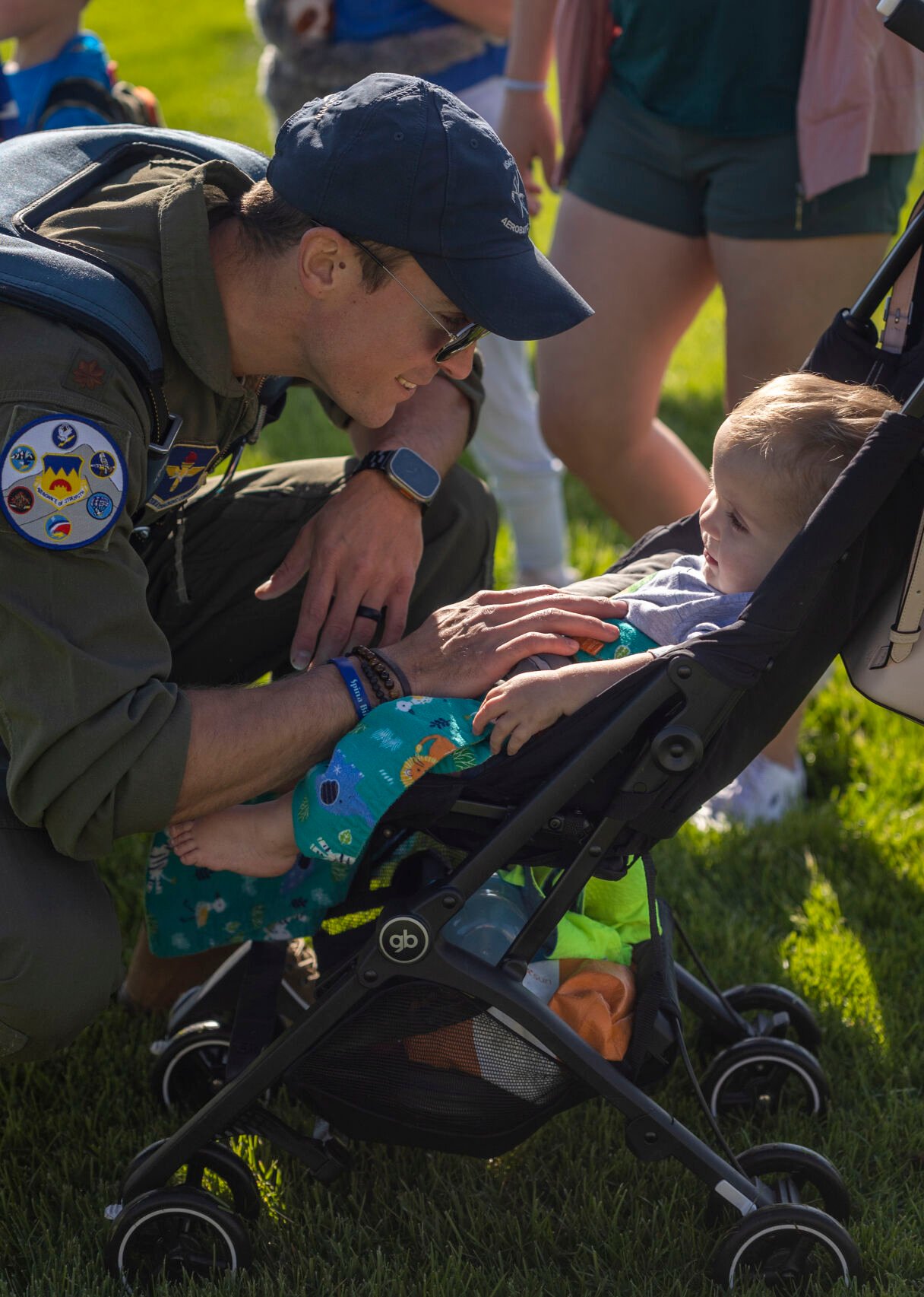 Major Alan Sosebee smiles to his one year old son Zeke after flying second as safety on one of the gliders that landed on Stillman Field at the U.S. Air Force Academy Class of 2023 Graduation Parade in Colorado Springs, Co., on Wednesday, May 31, 2023. His wife Kaitlyn Sosebee and four children rushed him with hugs after he and a team pushed the glider off the field. (Gabi Broekema)