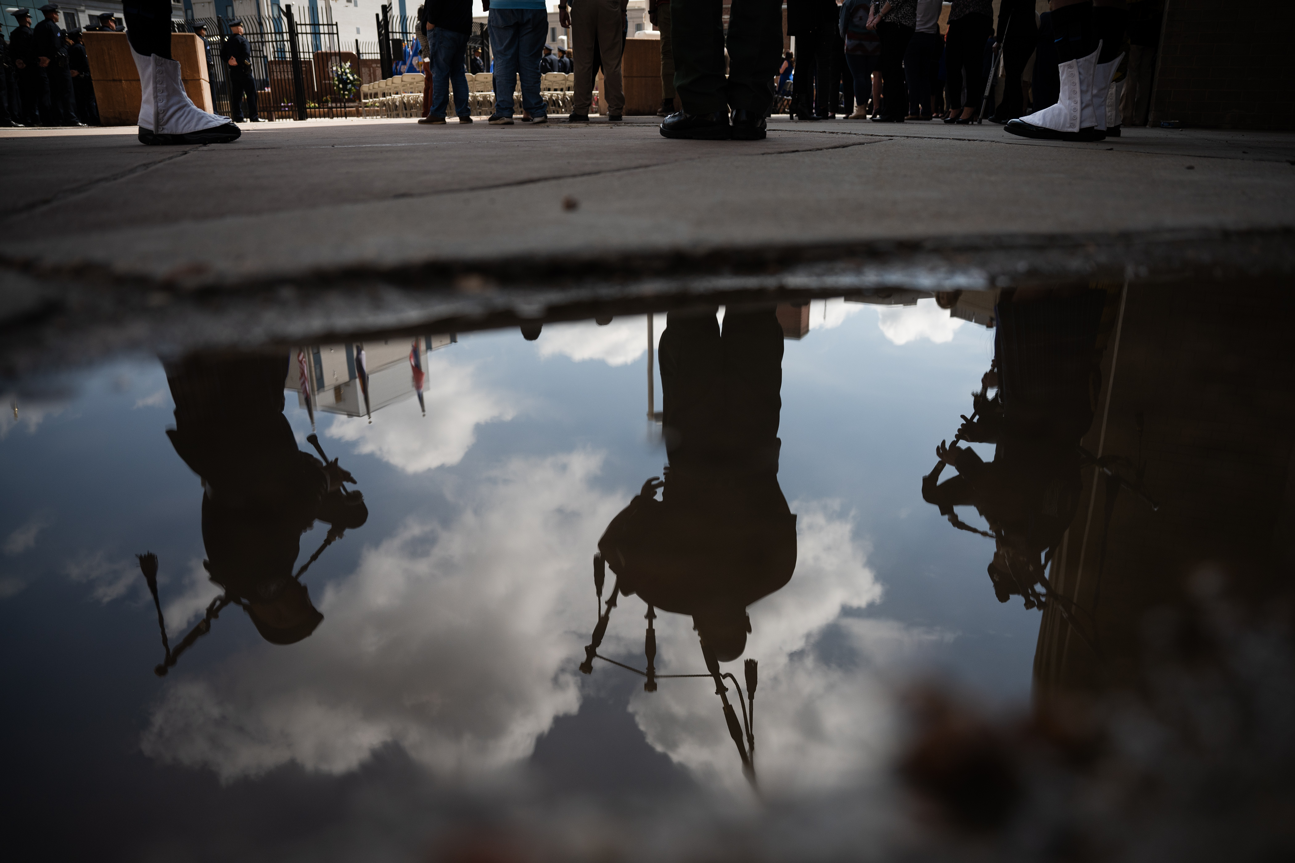Colorado Emerald Society Pipe and Drum bagpipers are reflected in a puddle while playing 