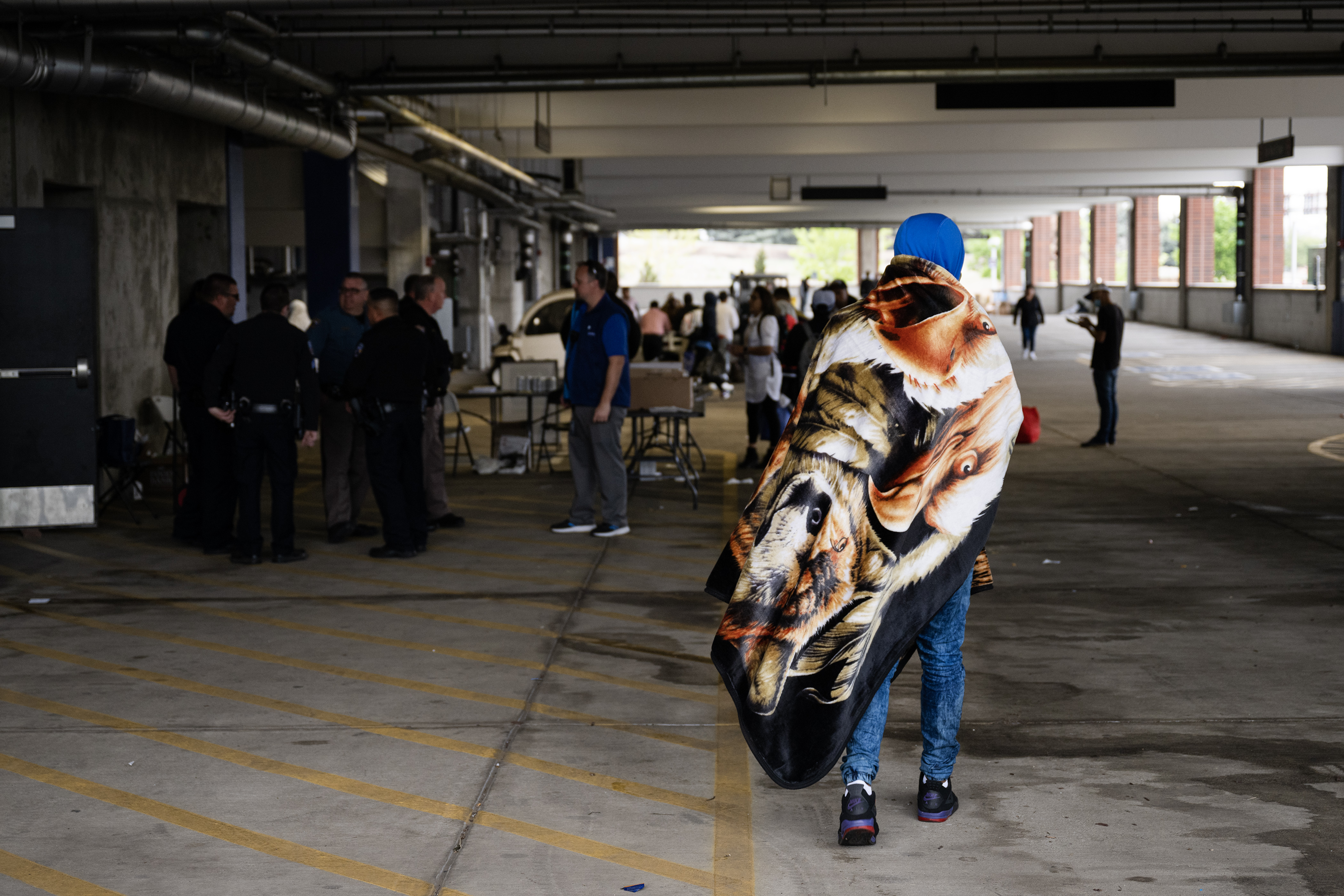 An immigrant wraps himself in a blanket while others are provided services in a blocked-off parking garage on Wednesday, May 10, 2023, on the Auraria Campus in Denver. (Timothy Hurst/Denver Gazette) (TimHursttim.hurst@gazette.comhttps://secure.gravatar.com/avatar/aca82bd62b4ee425c598527cd6faa1b1?d=mm&r=g)