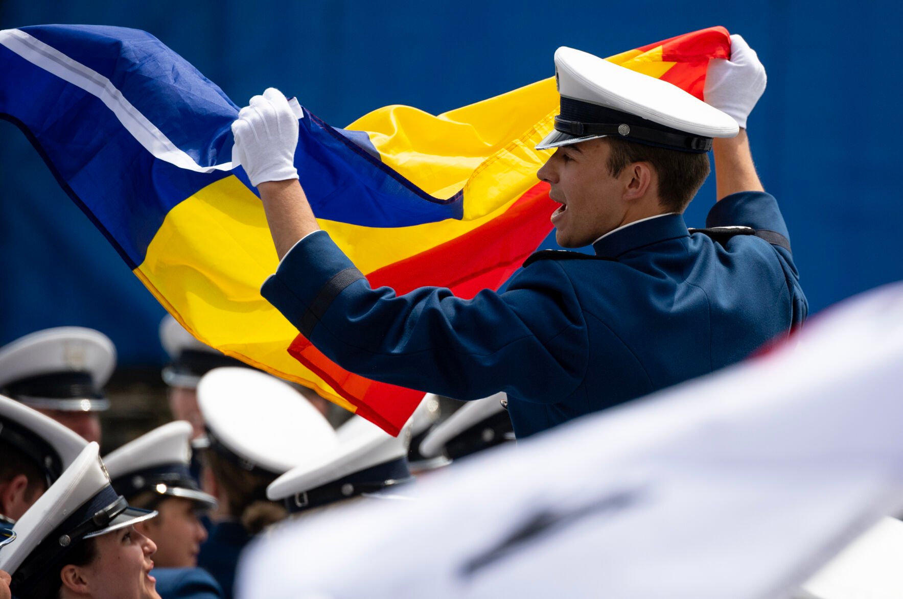 A cadet from Romania holds the Romanian flag as international students are recognized during the Air Force Academy graduation ceremony at Falcon Stadium on Thursday, June 1, 2023. (Parker Seibold, The Gazette) (Parker Seibold)