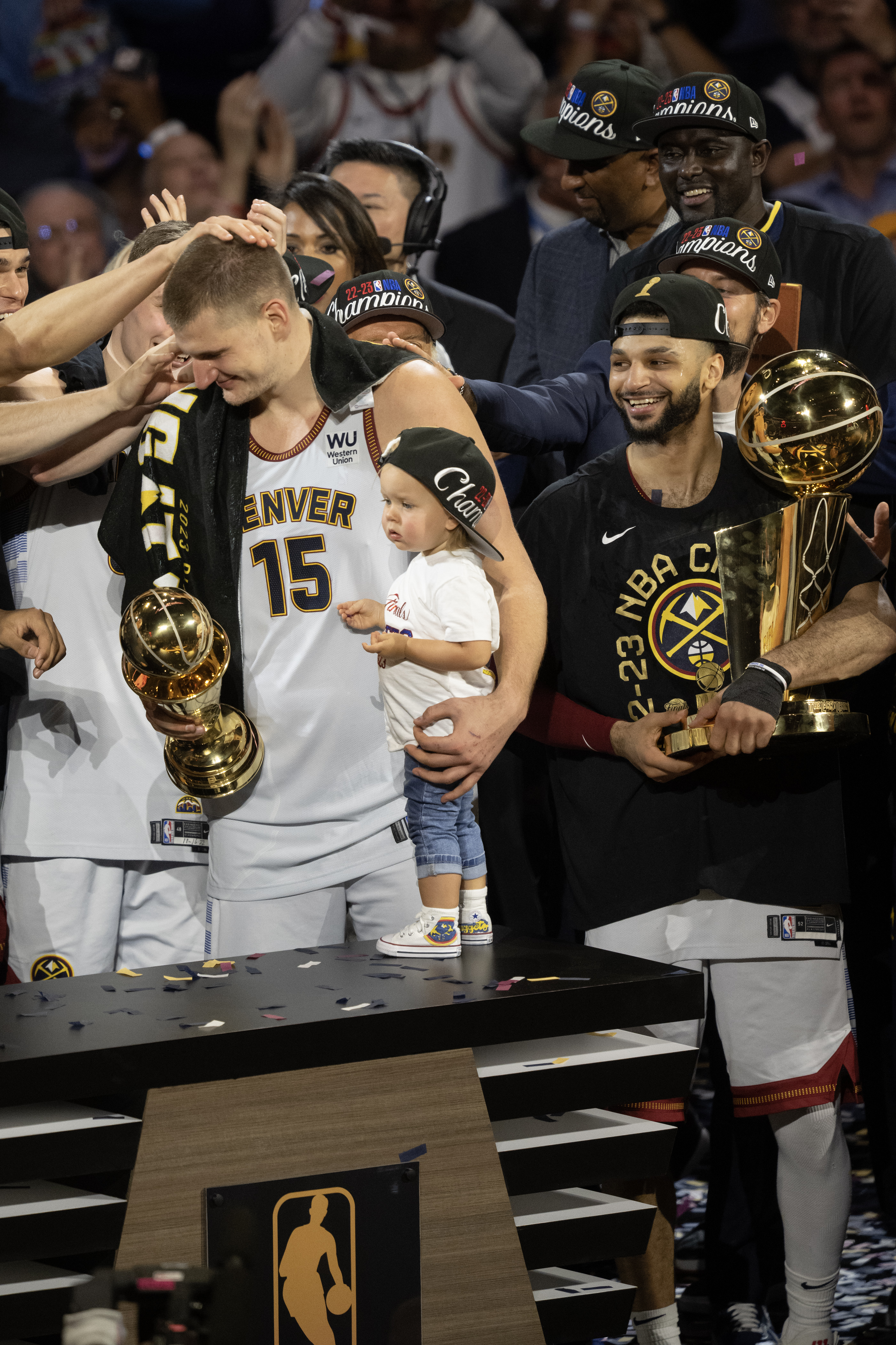 Teammates dote on Denver Nuggets center Nikola Jokic (15) as he’s presented with the Bill Russell NBA Finals Most Valuable Player Award while holding his daughter Ognjena after a 94-89 win over the Miami Heat in Game 5 of the NBA Finals on Monday, June 12, 2023, at Ball Arena in Denver. (Timothy Hurst/Denver Gazette) (TimHursttim.hurst@gazette.comhttps://secure.gravatar.com/avatar/aca82bd62b4ee425c598527cd6faa1b1?d=mm&r=g)