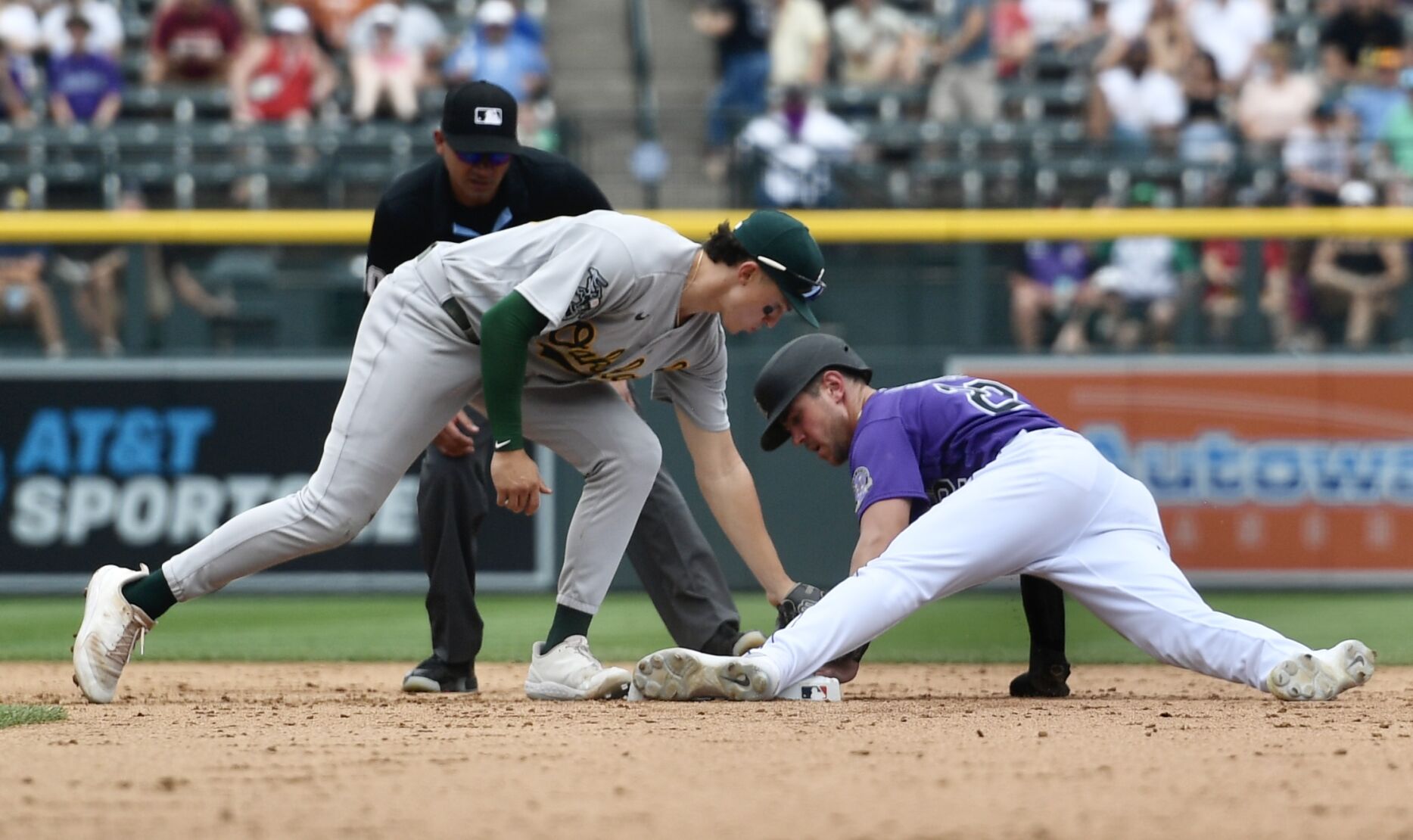 Rockies outfielder Nolan Jones avoids a tag from A's infielder Zack Gelof on Saturday, July 30, 2023. (CarsonFieldcarson.field@gazette.comhttps://secure.gravatar.com/avatar/c524ef3d384945349bed78d70eb2d2cd?d=mm&r=g)