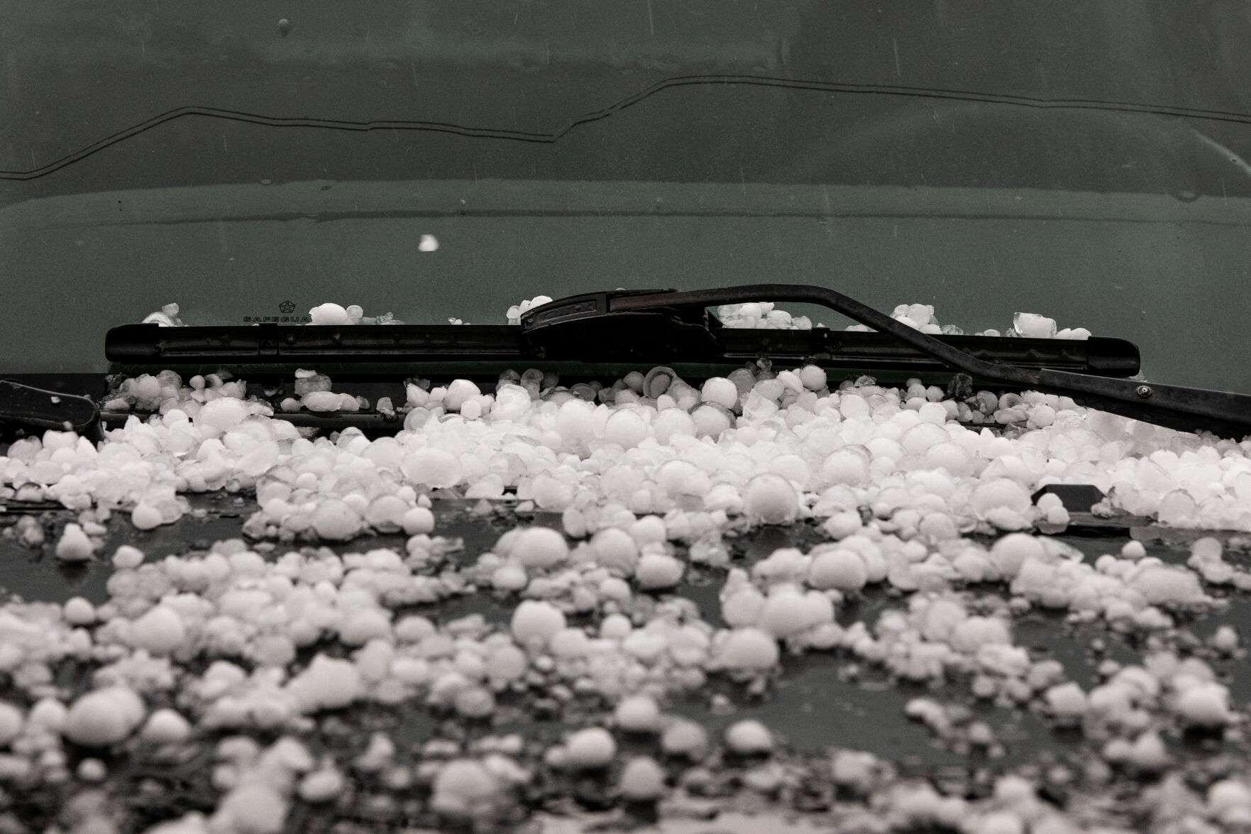 Hail sits under the windshield wiper of a parked vehicle after another hailstorm pelted Colorado Springs on Friday. (Parker Seibold, the gazette)