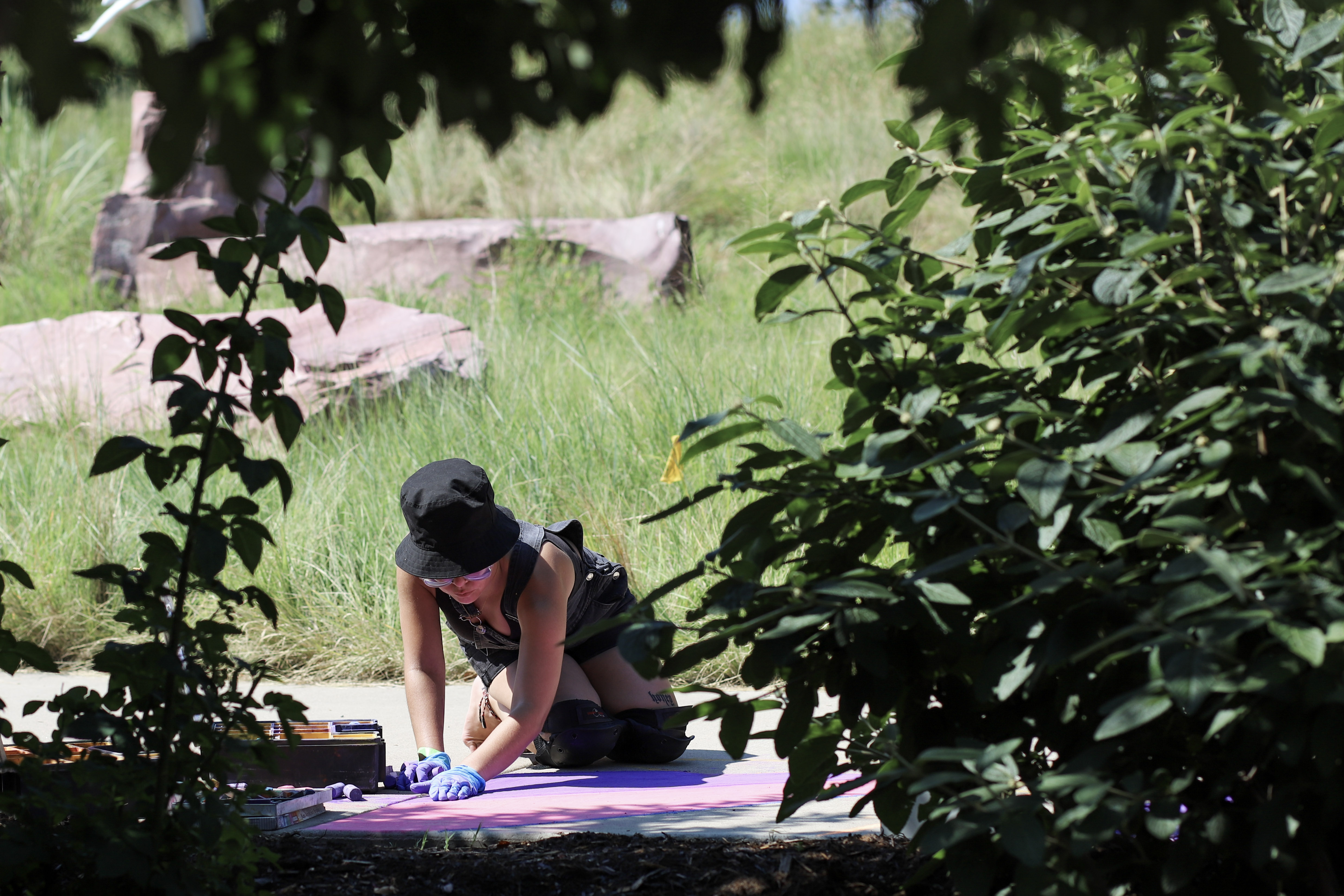 Nicole Fuentes-Vargas (@paintbynicole on Instagram) creates a chalk mural of light behind mountains at the 7/20 Foundation's 2023 annual Reflection Garden on Tap. (Kyla Pearce)