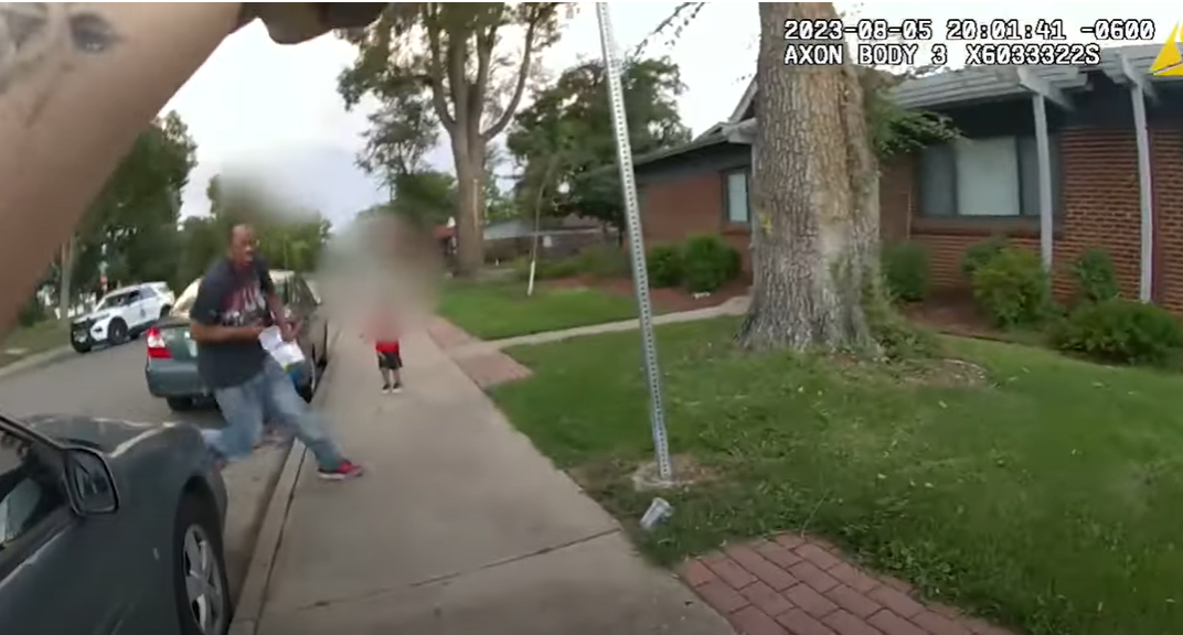 A Denver Police officer, gun drawn, faces off with Brandon Cole who appears to be running at her after being ordered to stop. A child and a woman with a laundry basket can be seen behind Cole, who was shot and killed immediately after this. Cole was unarmed. (Screen grab of Denver Police bodycam footage)