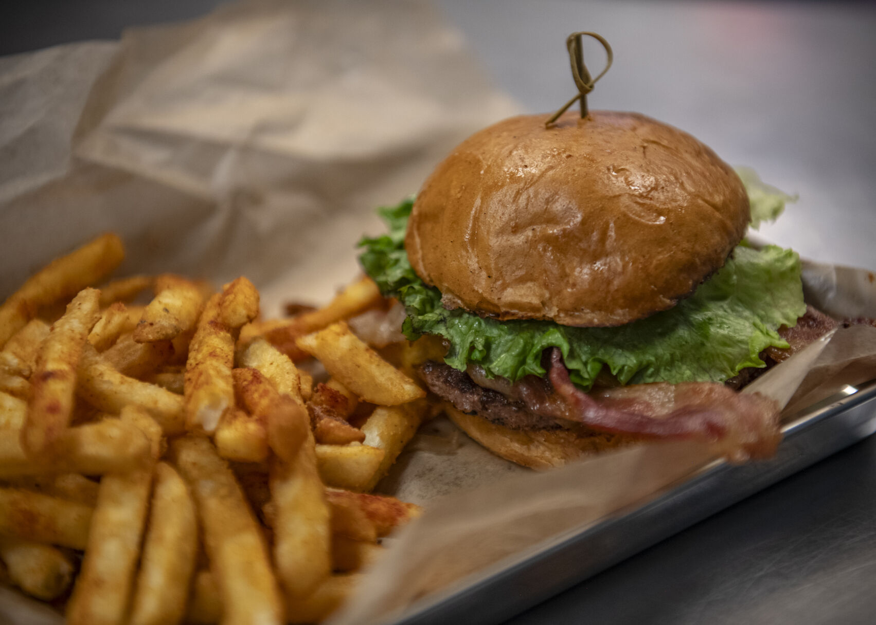 The Lebowski Burger is served with add-ons of bacon and cheese with a side of fries at Lebowski's Taproom in Colorado Springs, Colo. on Wednesday, August 23, 2023. (Gabi Broekema)