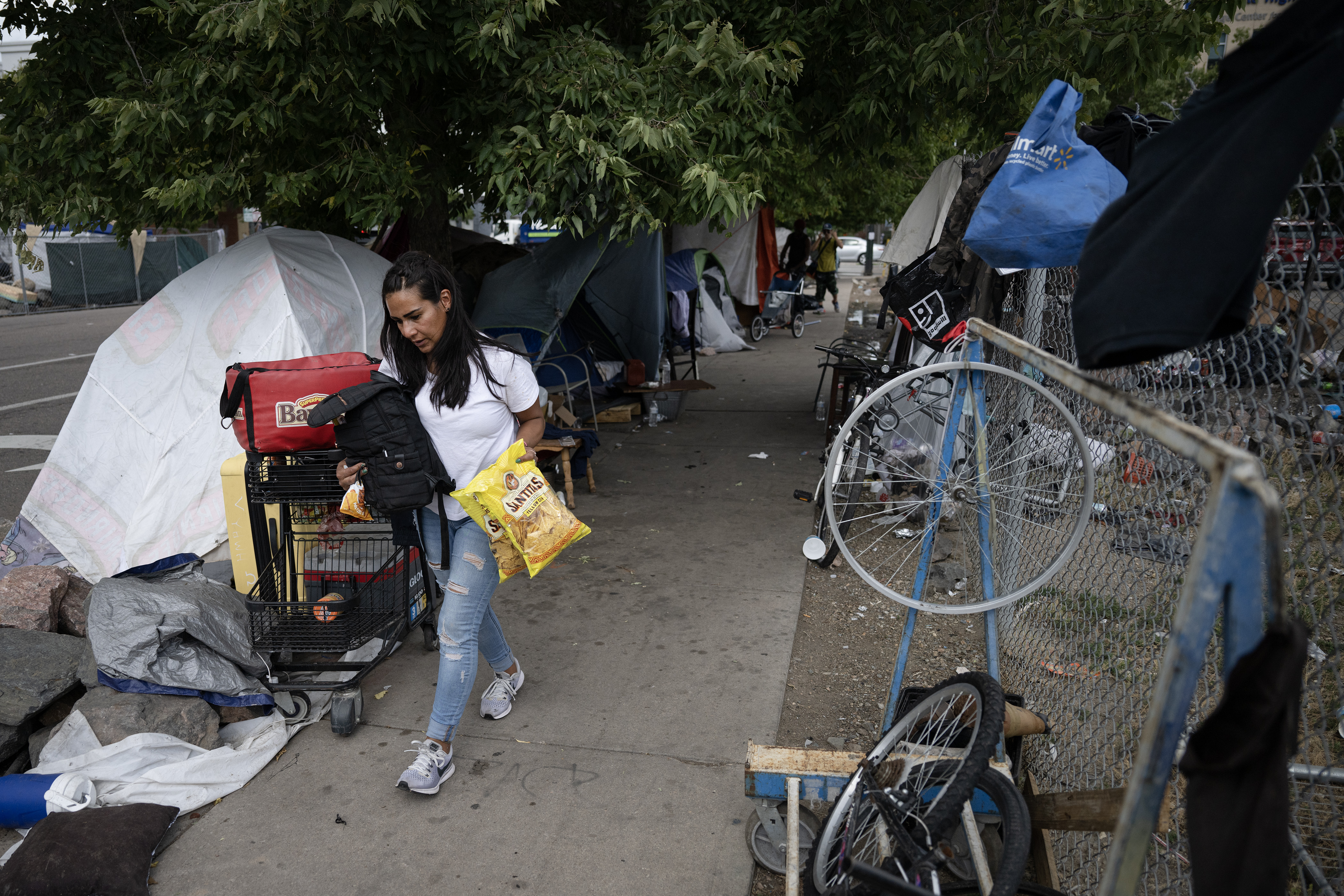 Melissa Hernandez, who is currently unhoused and living at an encampment at 22nd Street and Stout Street, grabs some provisions and head to another tent down the block on Thursday, Aug. 3, 2023, in Denver, Colo. (Timothy Hurst/Denver Gazette) (Timothy Hurst/Denver Gazette)