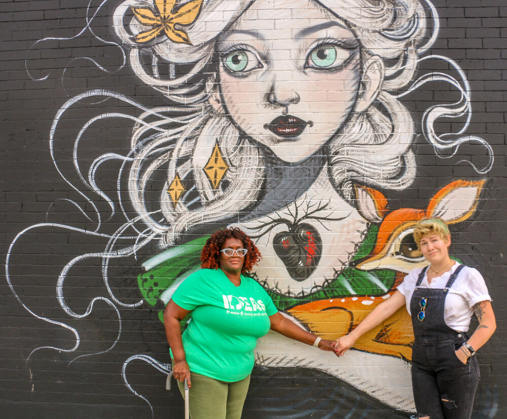 Alicia Young, left, and Emma Maxfield unite in front of a mural at the Second Nature hair salon on Aug. 11, 2023, in northwest Denver. That's next to the Bug Theatre, where both women are hosting separate events promoting workplace safety in area theaters over the next week. 'We must stop giving second chances to abusers,' Young says. (John Moore, Denver Gazette)
