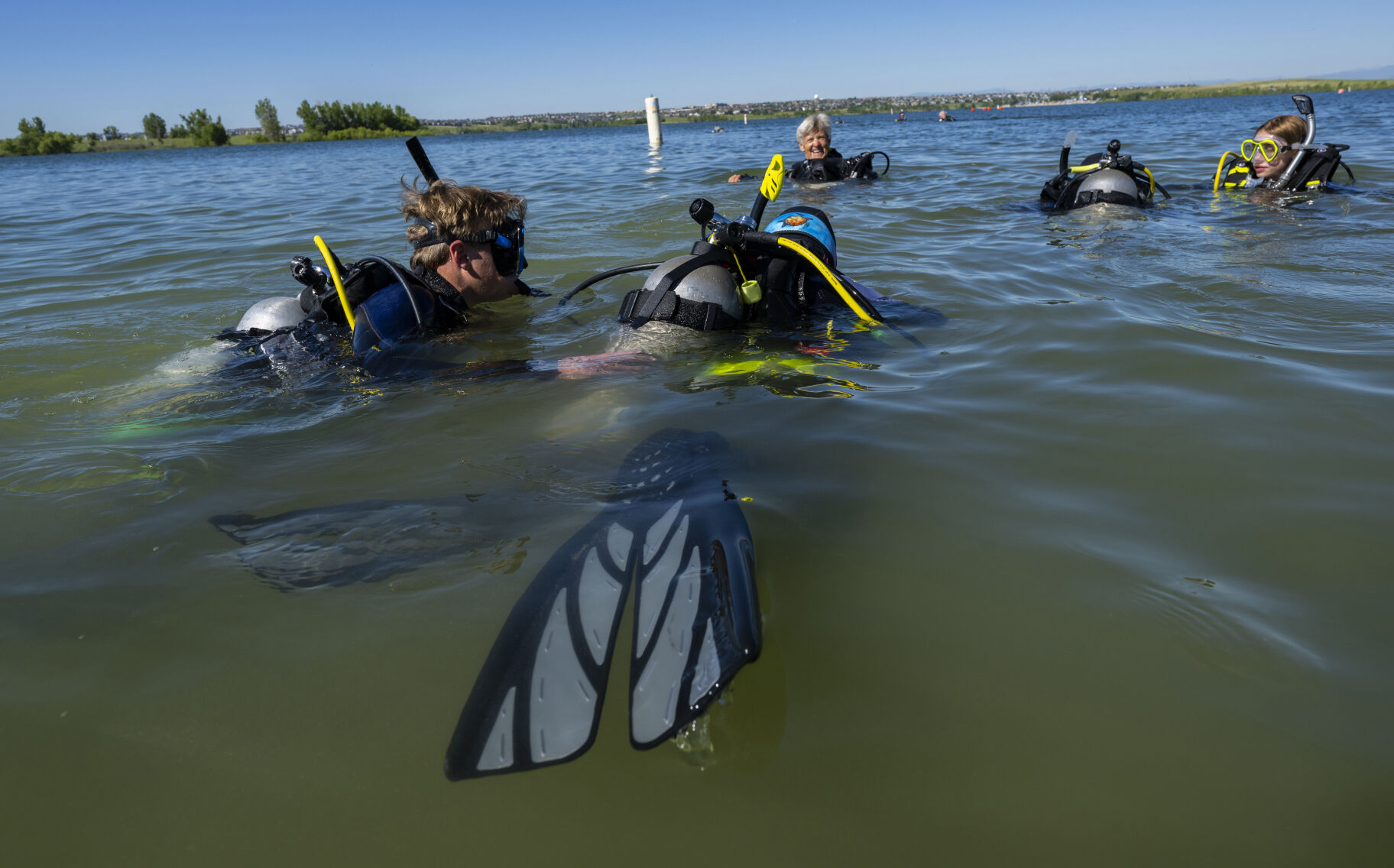 Tyler Henderson, 18, helps Owen Kinney, 10, as he learns to use a compass during their beginner diving class Sunday, July 16, 2023, at Aurora Reservoir near Denver. The class was through One World Dive & Travel. (Christian Murdock, The Gazette)
