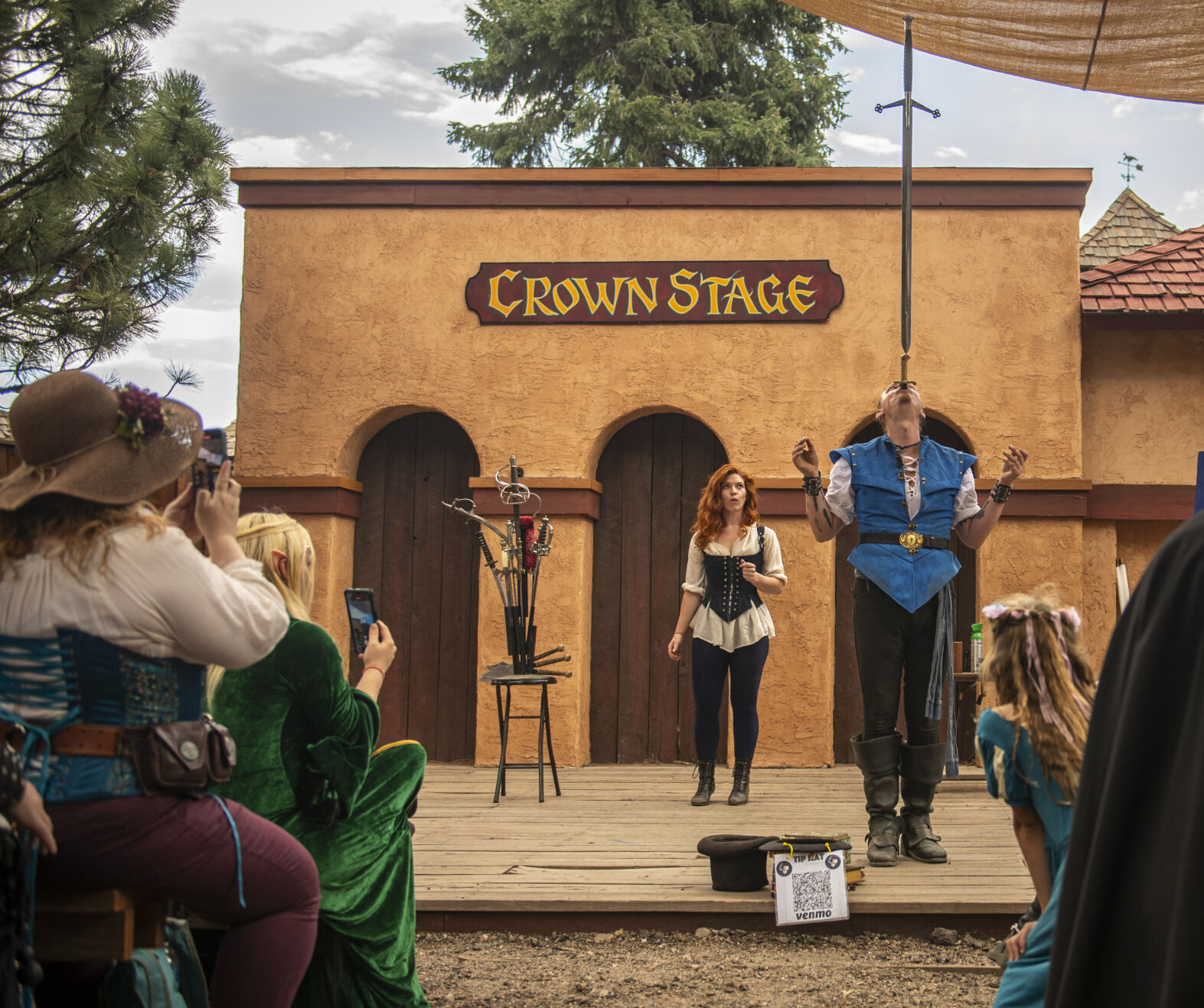 Sword swallower Cyrus Pynn of Tucson, California, completes his submission for the Guinness World Record for the longest time swallowing a sword while balancing another sword tip to pommel in front of an anxious crowd while being spotted by his fellow performer Sarah Bonnie of Colorado Springs on the Crown Stage at the Colorado Renaissance Festival on July 29, 2023. The record to beat was 20 seconds; he balanced for a minute and nearly 40 seconds. He has to submit his application before he is approved for holding the record. (Gabi Broekema)