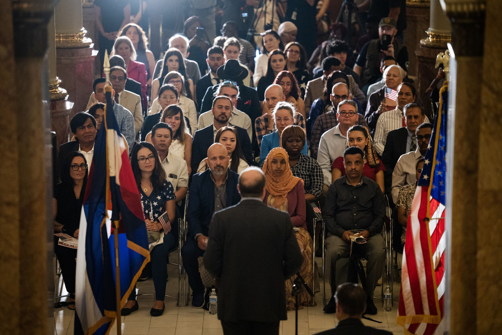 Soon-to-be U.S. citizens look on as Gov. Jared Polis gives remarks during a naturalization ceremony in the West Foyer of the Colorado State Capitol building on Tuesday, Aug. 1, 2023, in Denver, Colo. 35 new U.S. citizens from 20 different countries took the Oath of Allegiance from United States Citizenship and Immigration Services Kansas City district director David Douglas, held at the Capitol in celebration of the 147th anniversary of President Ulysses S. Grant signing a proclamation that officially declared Colorado a state. (Timothy Hurst/Denver Gazette) (TimHursttim.hurst@gazette.comhttps://secure.gravatar.com/avatar/aca82bd62b4ee425c598527cd6faa1b1?d=mm&r=g)