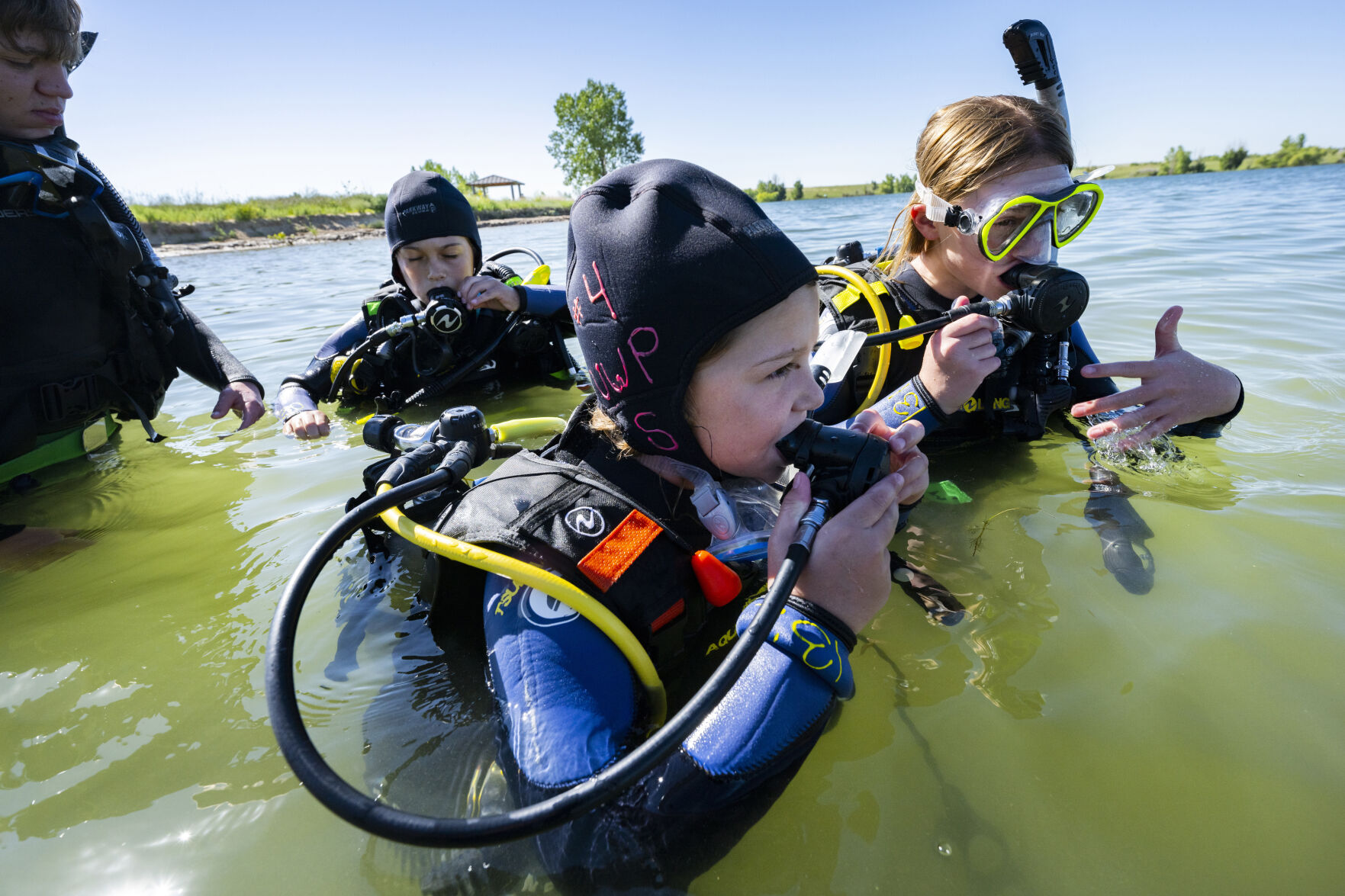 Avery Beebe, 10, front; her sister, Autumn Beebe, 12; and Owen Kinney, 10, test their regulators before going underwater during a beginner diving class taught by One World Dive & Travel on Sunday, July 16, 2023, at Aurora Reservoir near Denver. (photos by Christian Murdock, The Gazette)