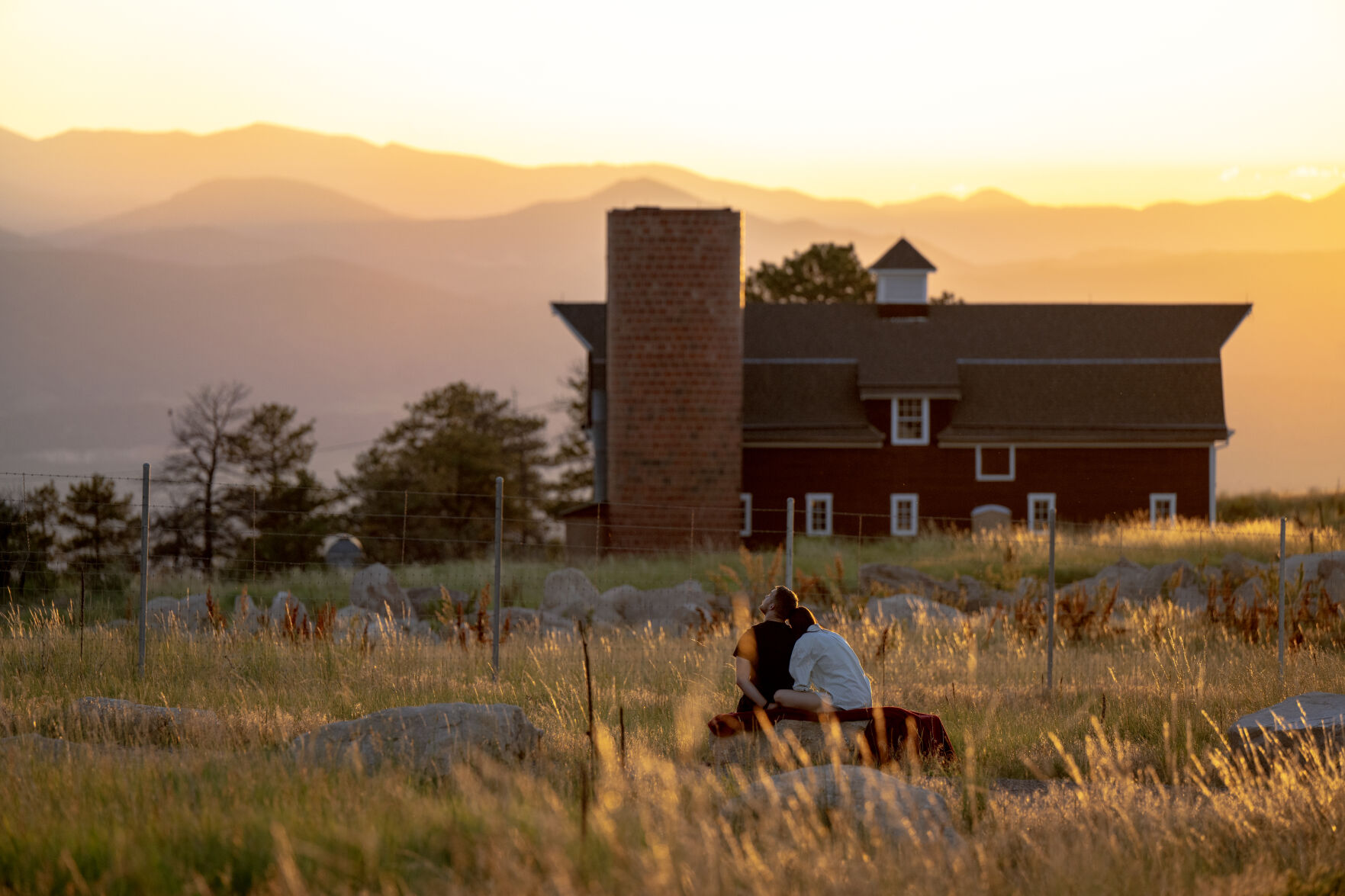 Nick Green, left, and Julia Paterek embrace as they watch the sun set over peaks seen in the expansive view from Daniels Park on July 11. (photos by Parker Seibold, the tribune)