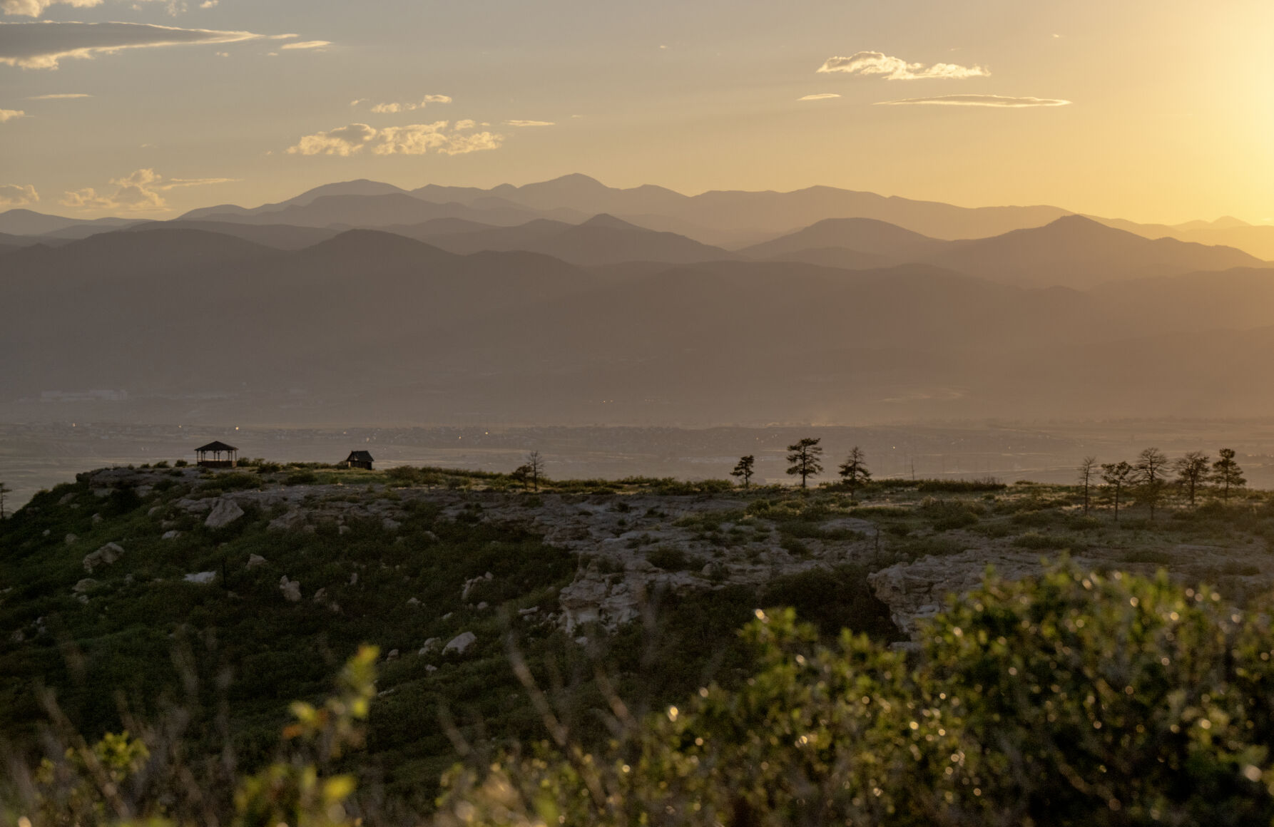 The sunset creates depth to mountains seen from an overlook high above a sweeping, green floor spotted with bluffs and buttes at Daniels Park on July 11. Mountains spanning from Pikes Peak to Longs Peak to Wyoming’s Mummy Range can be seen from different vistas lining Daniels Park Road. (photos by Parker Seibold, the tribune)