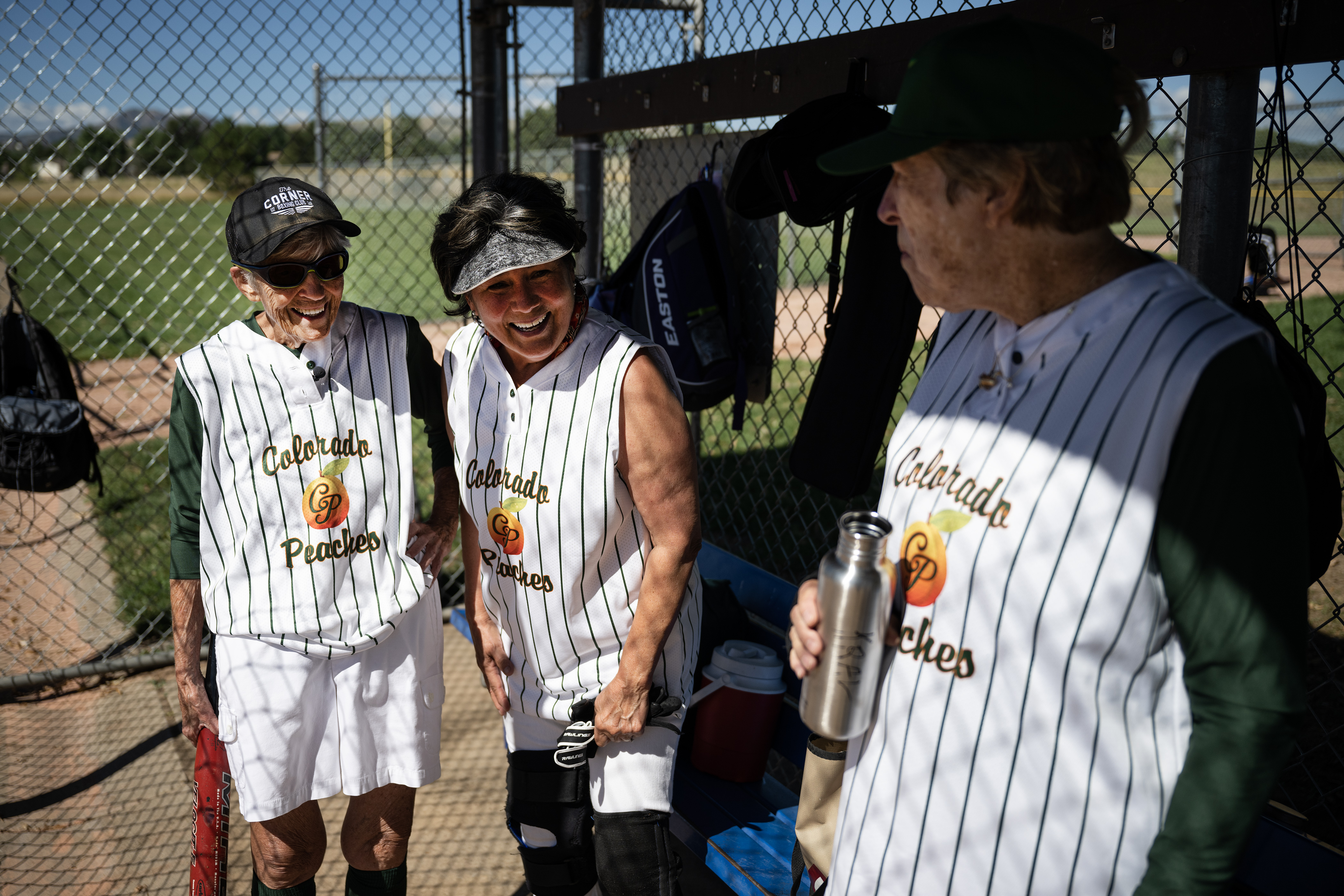 Colorado Peaches Turnovers players, from left, “Maggie” McCloskey (13), Dora Haynes (50) and Midge Kral (62) share a laugh in the dugout before a game against the Tarts during the Second Annual Gail Klock Memorial Peach Bowl on Tuesday, Aug. 29, 2023, at Addenbrooke Park in Lakewood, Colo. (Timothy Hurst/Denver Gazette) (TimHursttim.hurst@gazette.comhttps://secure.gravatar.com/avatar/aca82bd62b4ee425c598527cd6faa1b1?d=mm&r=g)