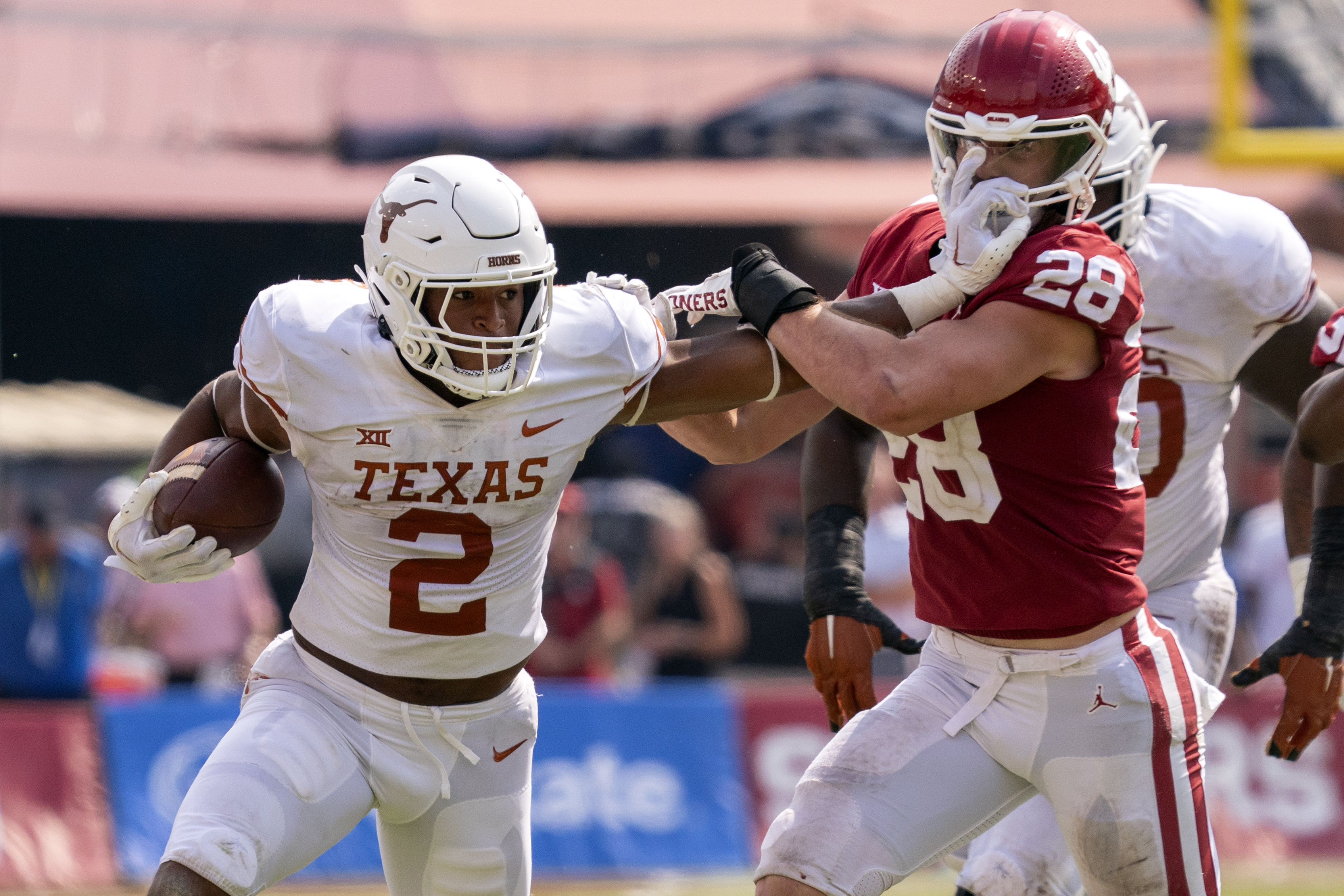 Texas running back Roschon Johnson (2) stiff-arms Oklahoma linebacker Danny Stutsman (28) on a run during the second half of an NCAA college football game at the Cotton Bowl, Saturday, Oct. 8, 2022, in Dallas. Texas won 49-0. (AP Photo/Jeffrey McWhorter) (Jeffrey McWhorter)