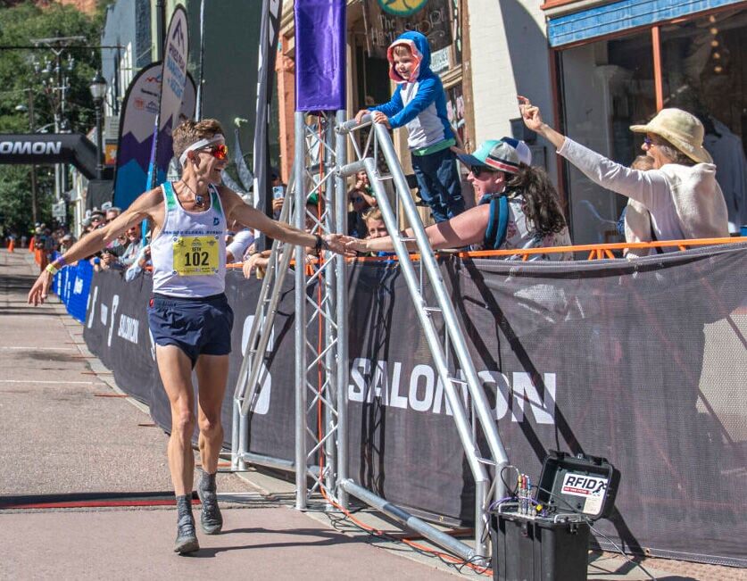 Pikes Peak Marathon 2023 runner-up Seth DeMoor reaches out to his wife Brigid DeMoor as one of his 6 children and other supporters cheer him on at the finish line of the Pikes Peak Marathon in Manitou Springs on Sunday, September 17, 2023. Though DeMoor was 2nd place overall, he was the first Doubler to finish the Marathon. “It was so fun to cheer him on,” Bridgid said. “He’s perfect.”