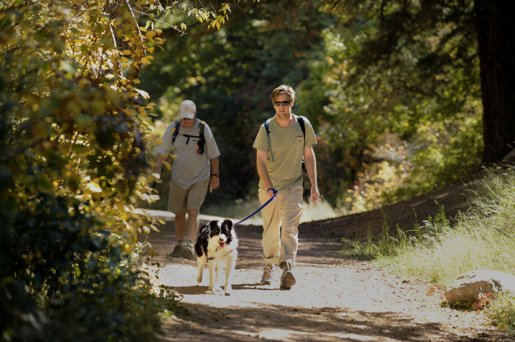 Patrick Sullivan walks his dog Dougal, as Barry Sullivan walks behind, on the Lower Columbine Trail as colors start to show in early October in this file photo. (gazette file)