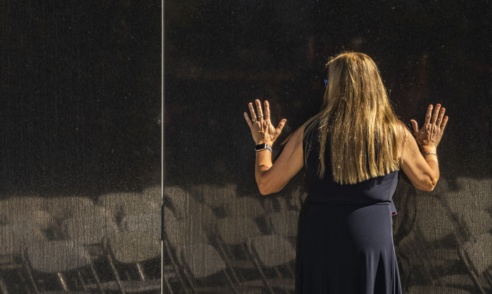As families and friend bustle and crowd the from to the new section of the Fallen Fire Fighter Memorial, Nancy Komenda-Rapp of Indianapolis, Indiana takes a quiet moment on the opposite side of the wall featuring the new etchings of the 572 fallen fire fiighters in Memorial Park on Saturday, September 16, 2023. Komenda-Rapp was visiting to honor her husband Mark Rapp who passed away in 2022. (Gabi Broekema)