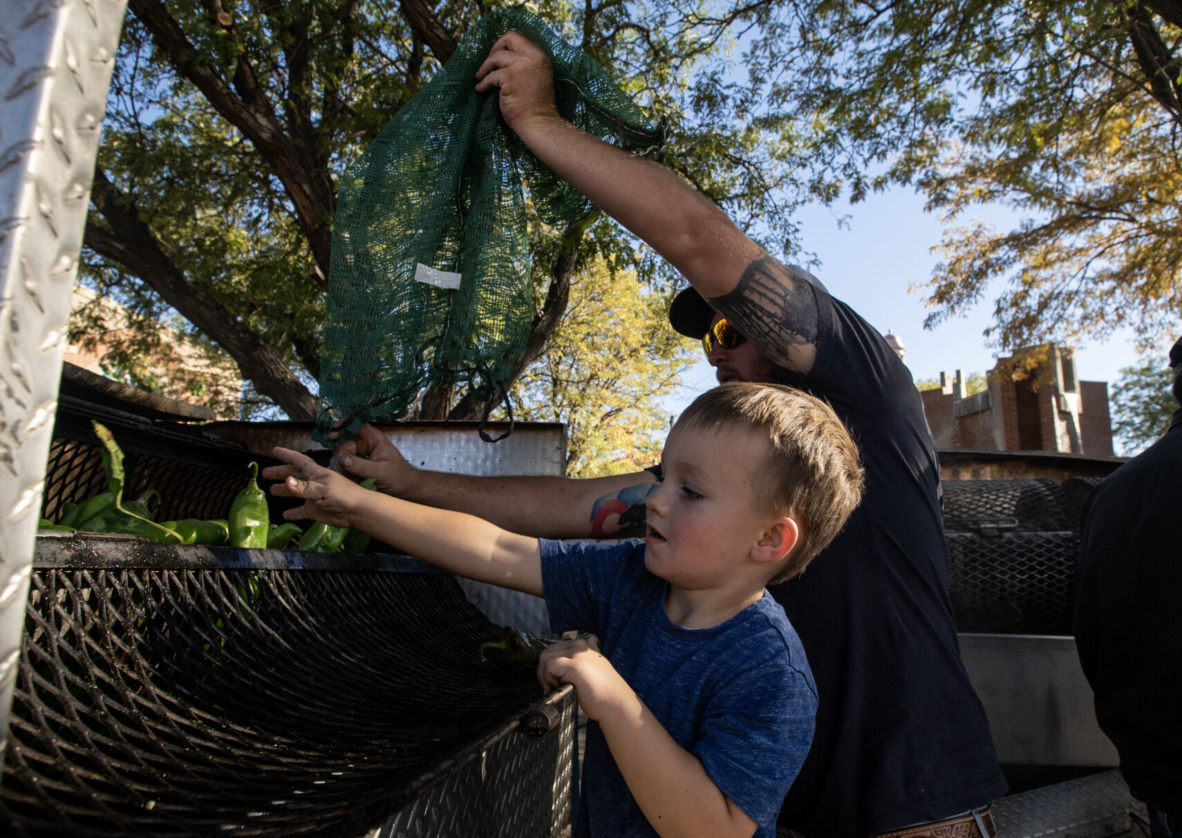 Five-year-old Clayton Milberger helps Bryce Eagan load chiles into a roaster on the first day of the 29th Annual Pueblo Chile and Frijoles Festival in Pueblo, Colo., on Friday, Sept. 22, 2023. The festival continues on Saturday from 10 a.m. to 12 a.m. and Sunday from 10 a.m. to 5 p.m. (Parker Seibold, The Gazette) (Parker Seibold)