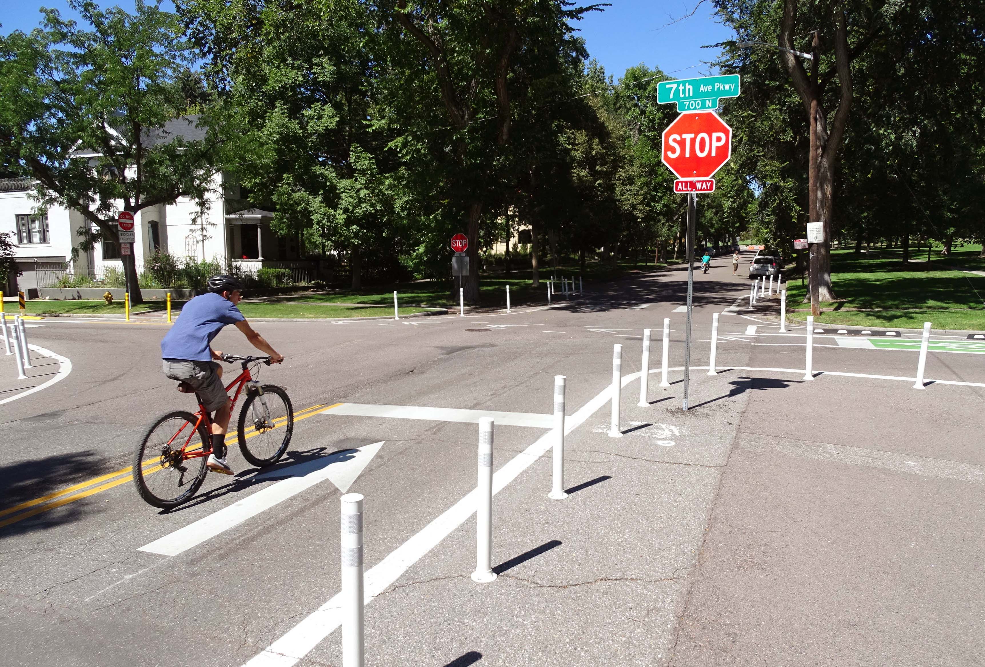 A cyclist navigates a channel of protected lanes lined by vertical bollards, in the wake of the most recent modifications at Seventh Avenue and Williams Street, beside Little Cheesman Park. Residents have tracked five accidents near the intersection since the infrastructure was installed, in addition to reported close calls. (Mark Samuelson/Special to The Denver Gazette)