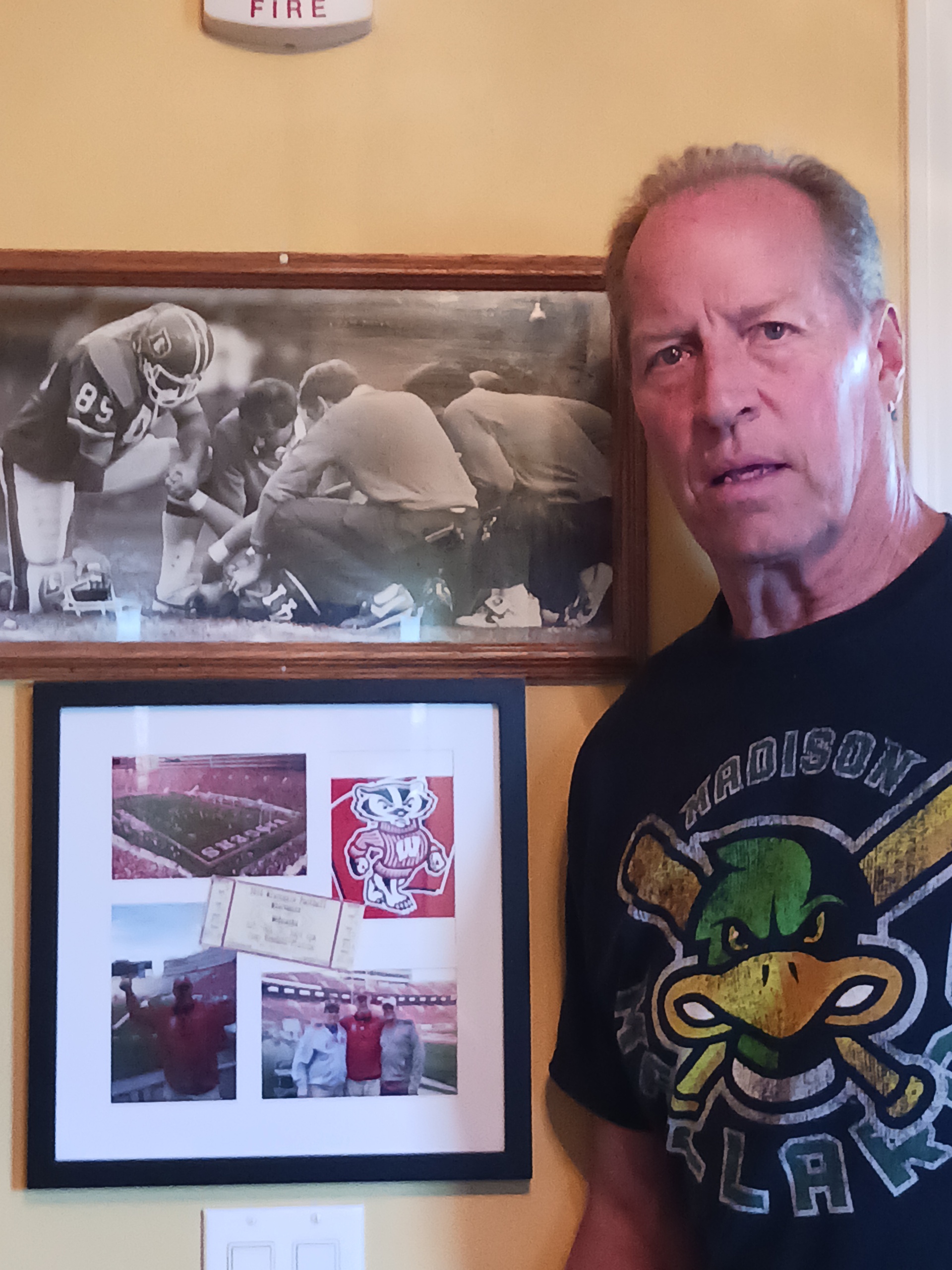 Former Broncos tight end Ron Egloff stands next to a photo on the wall at his Denver home. Egloff is shown comforting late running back Rob Lytle, who played for the Broncos from 1977-83, after he suffered an injury late in his career. (Courtesy of Ron Egloff). (Courtesy Ron Egloff)