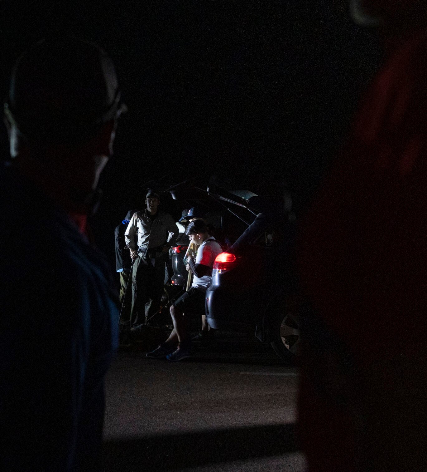 Team Red, White & Blue members get ready by headlamp and car lights for their trek of Barr Trail on September 10, 2023. Team Red, White and Blue is a nonprofit organization focused on providing a health and wellness community for veterans. (Gabi Broekema)
