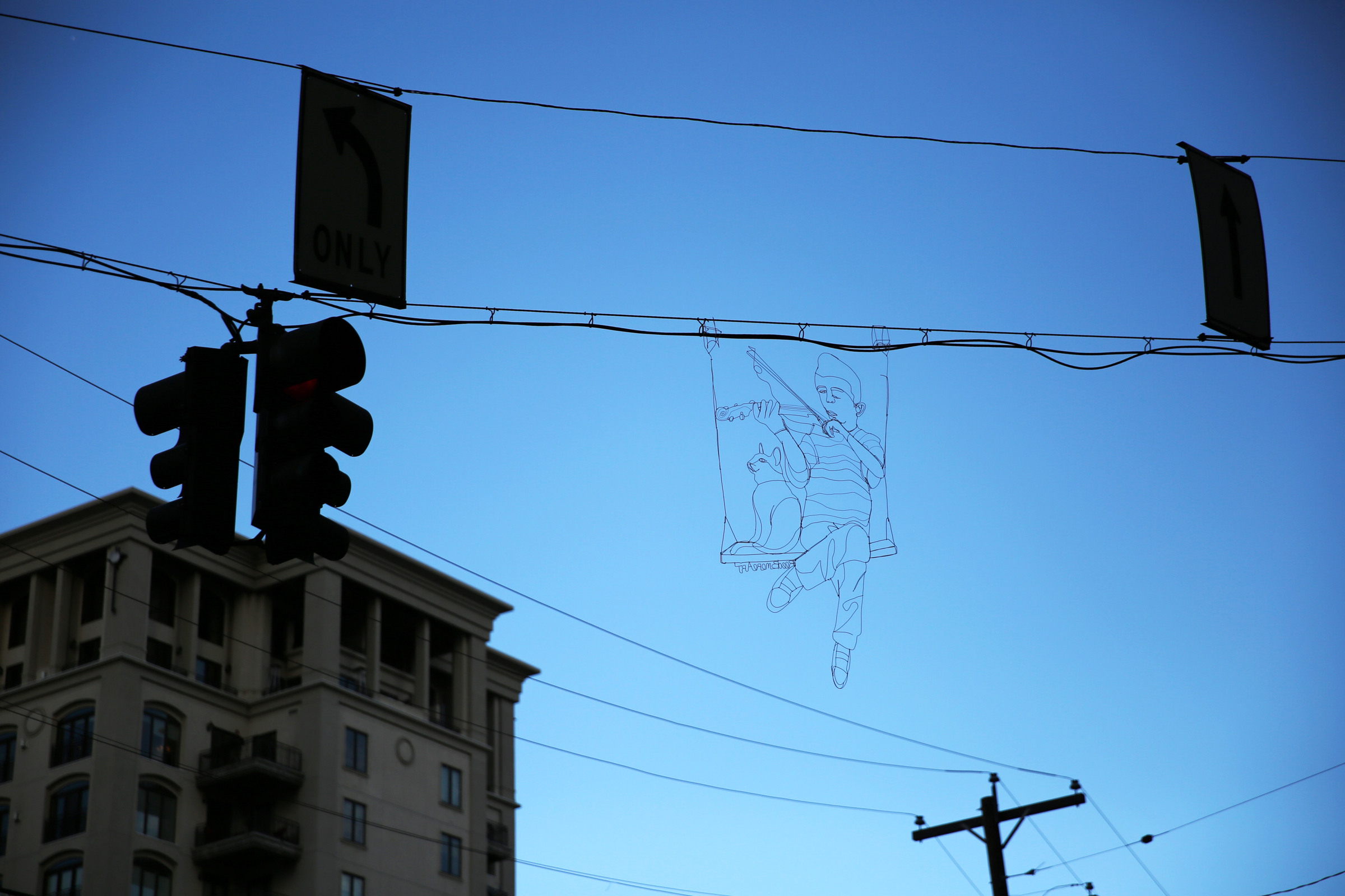 A wire piece of artwork depicting Elijah McClain playing a violin rests on a street light wire at the intersection of Sherman Street and 18th Avenue in downtown Denver on Dec. 2, 2020. (Forrest Czarnecki/The Gazette) (Forrest Czarnecki)