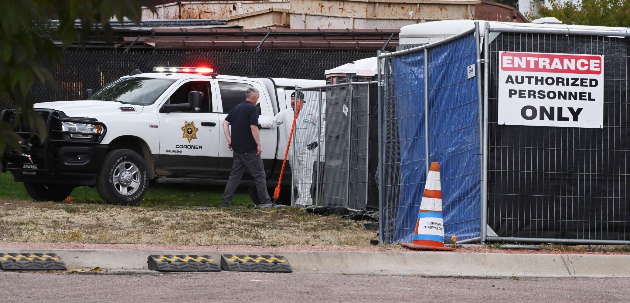 Deliveries of the remains of the 115 decomposing bodies discovered at the Return to Nature Funeral Home in Penrose, Colorado, have started arriving at the El Paso County Coroner’s Office in Colorado Springs, Colorado on Tuesday, Oct. 10, 2023. Authorities talk inside the enclosure after one of the drop-offs. Temporary structures and refrigerated trucks filled a parking lot next to the office where they will be beginning the massive task of trying to identify the remains. (Photo by Jerilee Bennett, The Gazette) (JERILEE BENNETT, THE GAZETTE)