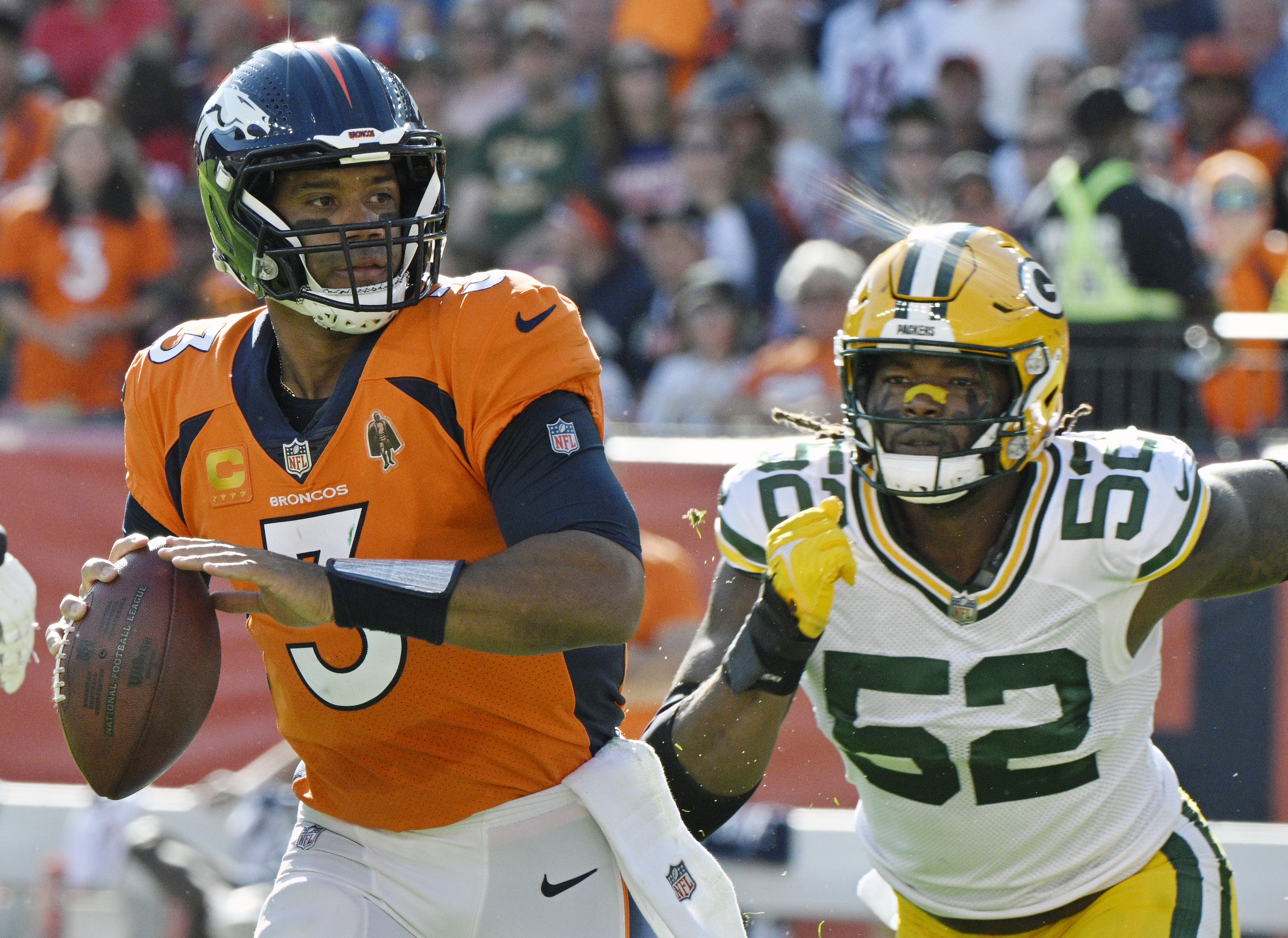 Denver Broncos quarterback Russell Wilson (3) looks downfield while being pursued by Green Bay Packers linebacker Rashan Gary (52) before throwing a pass while being pursued during a game at Empower Field at Mile High on Sunday, Oct. 22, 2023. (Photo by Jerilee Bennett, The Gazette)