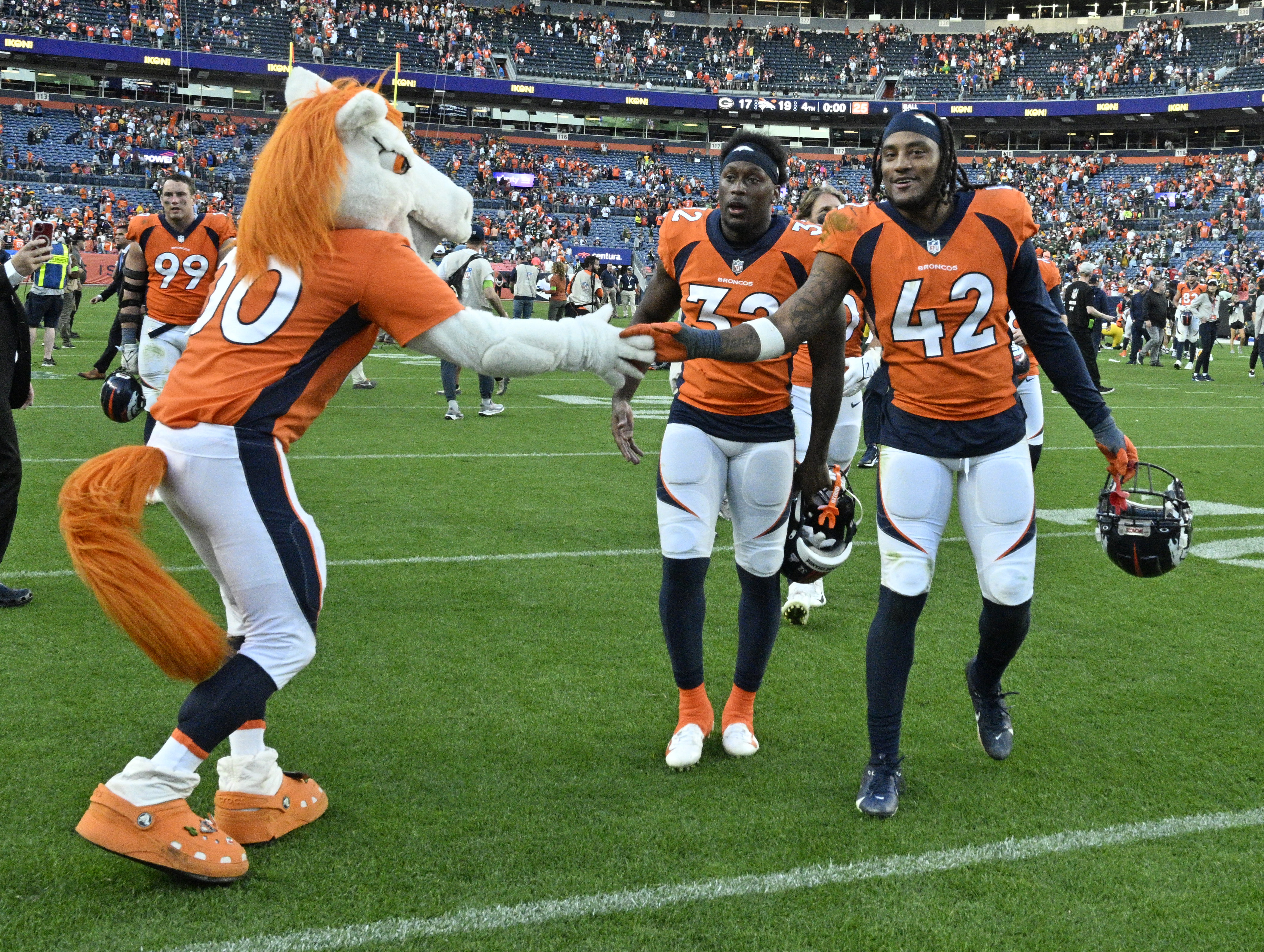 Denver Broncos safety Delarrin Turner-Yell (32) and Denver Broncos linebacker Nik Bonitto (42) are greeted by Miles after a win against the Packers at Empower Field at Mile High on Sunday, Oct. 22, 2023. (Photo by Jerilee Bennett, The Gazette)
