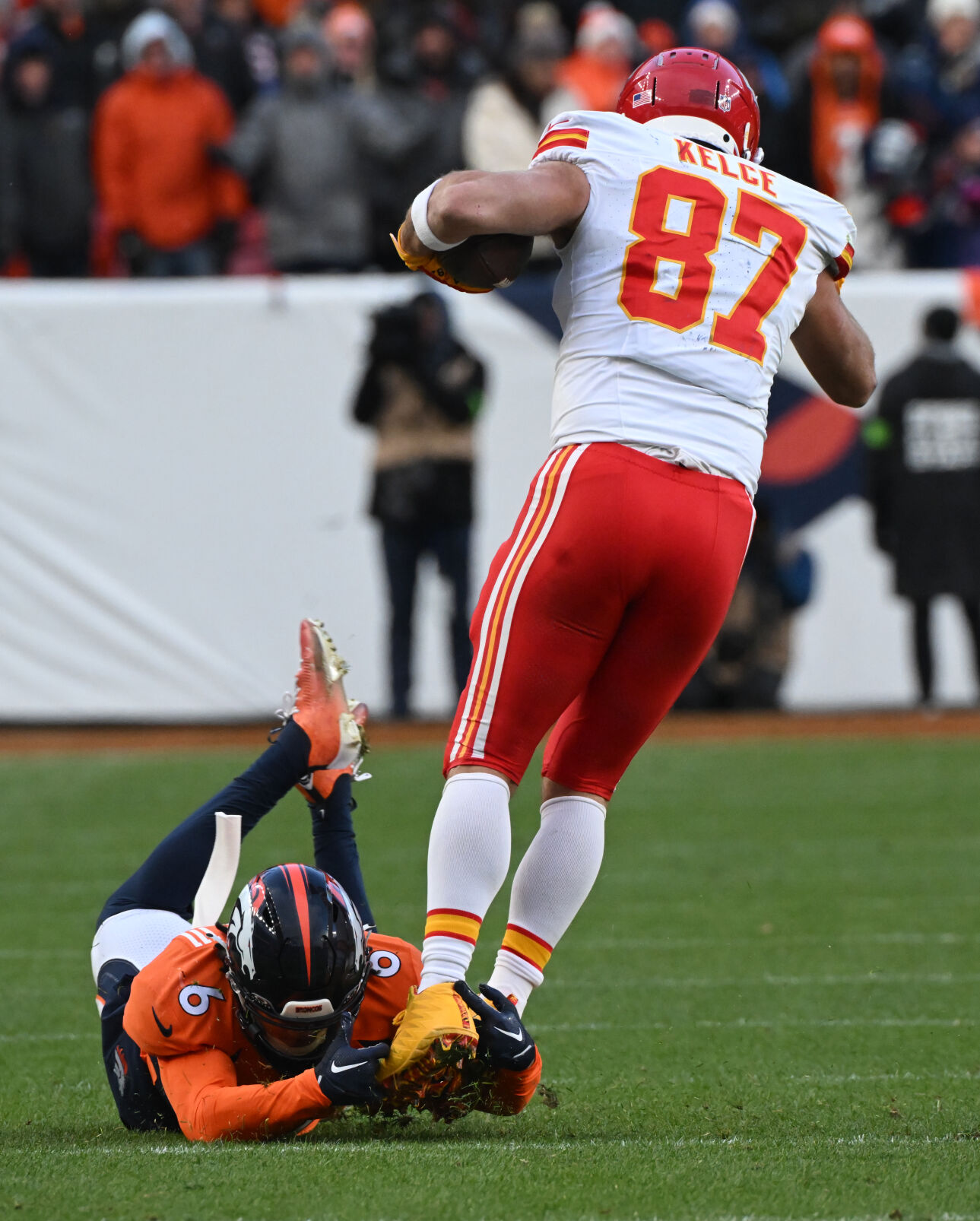 Denver Broncos safety P.J. Locke (6) gets a hold of Kansas City Chiefs tight end Travis Kelce (87) by the ankles and brings him down during a game at Empower Field at Mile High on Sunday, Oct. 30, 2023. The Broncos defeated the Chiefs 24-9. (Photo by Jerilee Bennett, The Gazette)