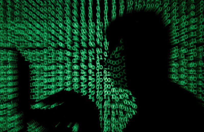 FILE PHOTO: A man holds a laptop computer as cyber code is projected on him in this illustration picture. (Kacper Pempel/Reuters)