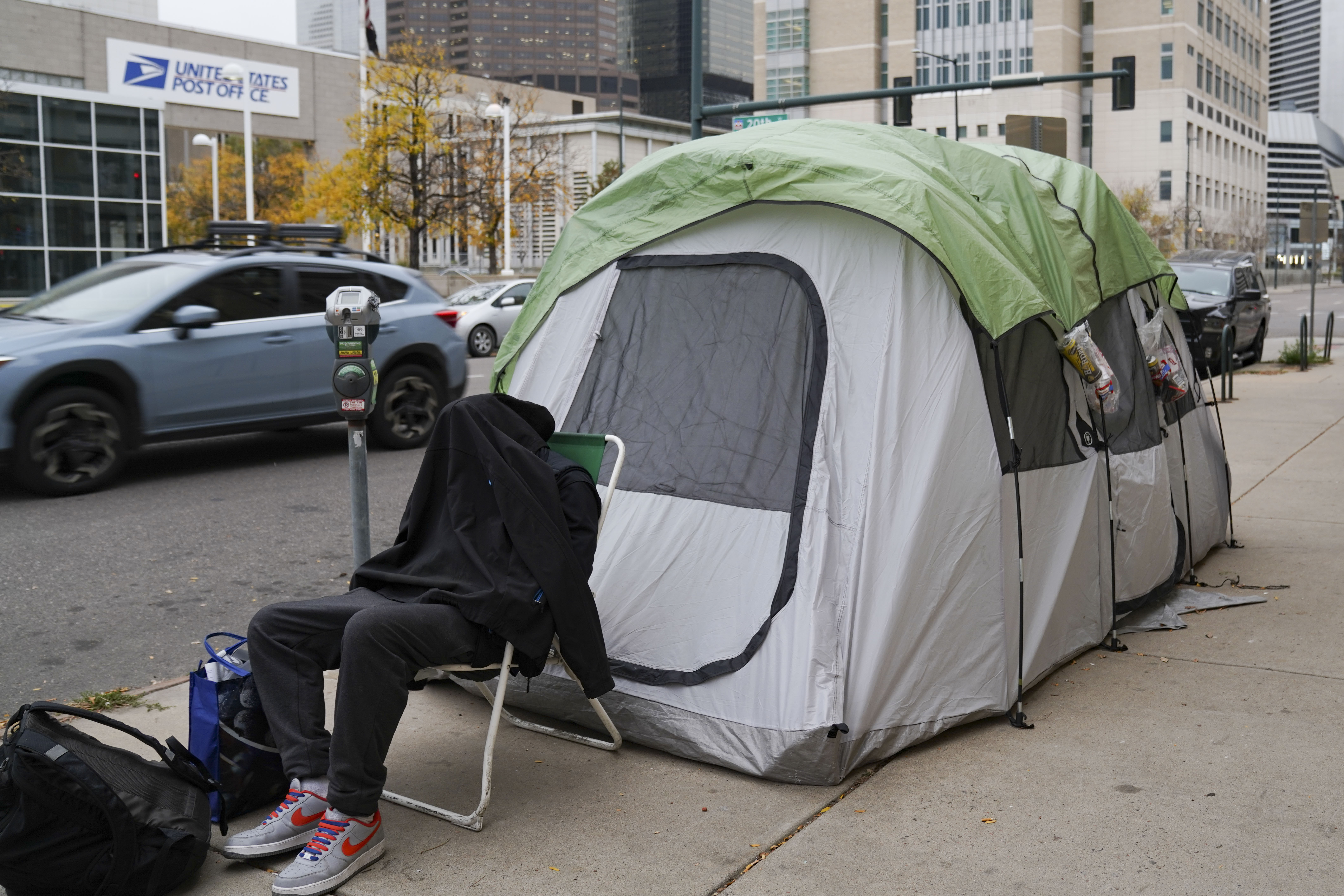 An individual sits outside of a tent with a coat over their head near 21st and Curtis Street on Thursday, Oct. 26, 2023 in Denver, Colorado. Some 50 homeless people at the encampment are being offered hotel housing as cold weather approaches, according to the mayor’s office. The city is planning to sweep the encampment. (PHOTO: Rebecca Slezak/Special to The Denver Gazette) (Rebecca Slezak)