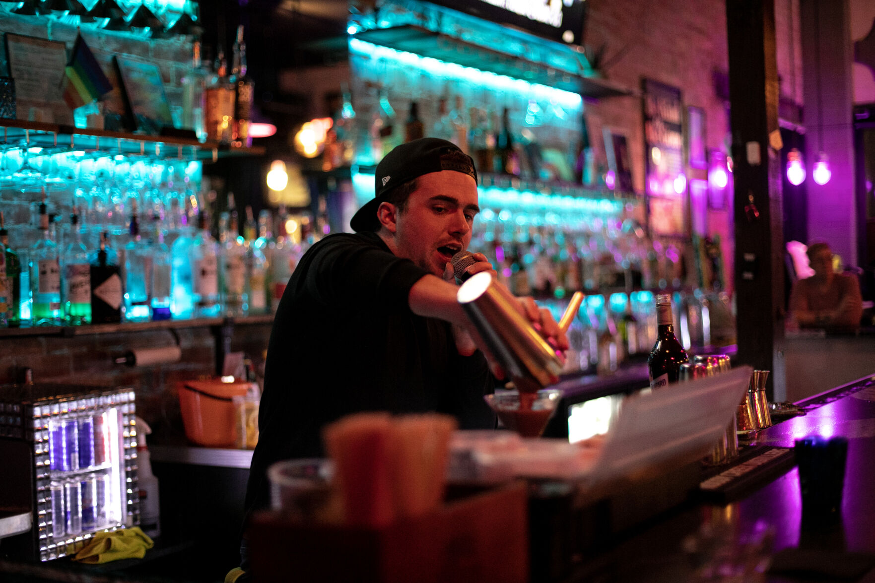 Mark Autry, a bartender at Icons, sings as he pours a martini Thursday. The downtown bar is known for its singing bartenders. (Photos by Parker Seibold, the gazette)