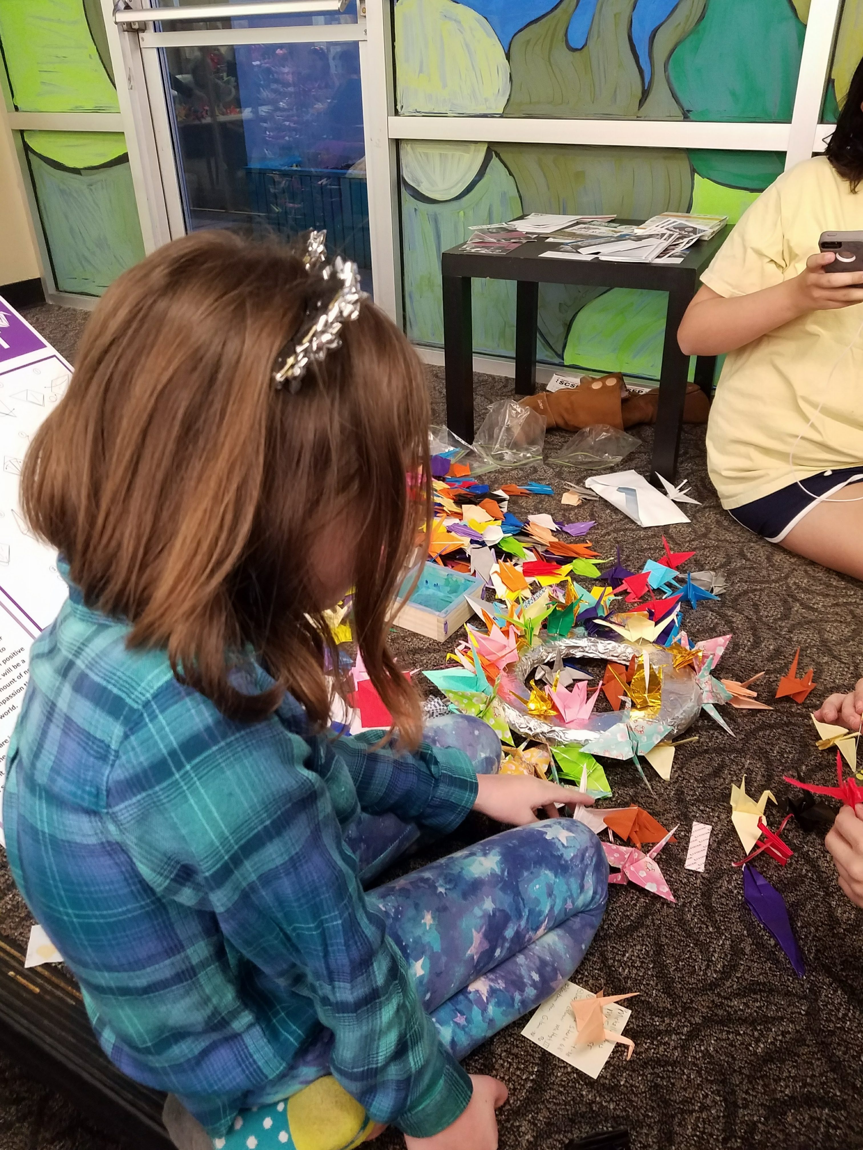 A person helps make paper cranes for the 7/20 Memorial Foundation. (Courtesy: 7/20 Memorial Foundation)
