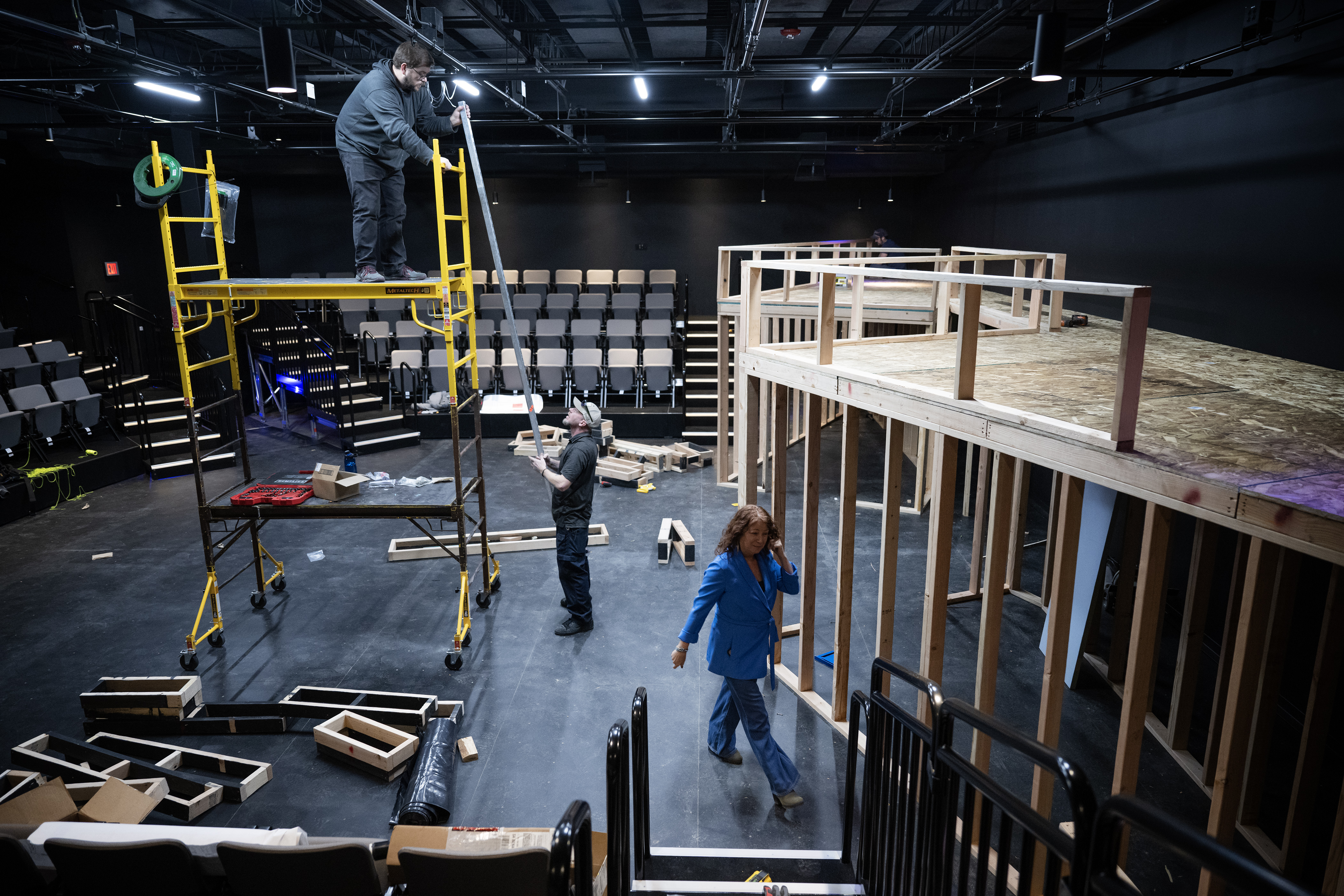 Executive director Lisa DeCaro walks past crew members as they build the set for