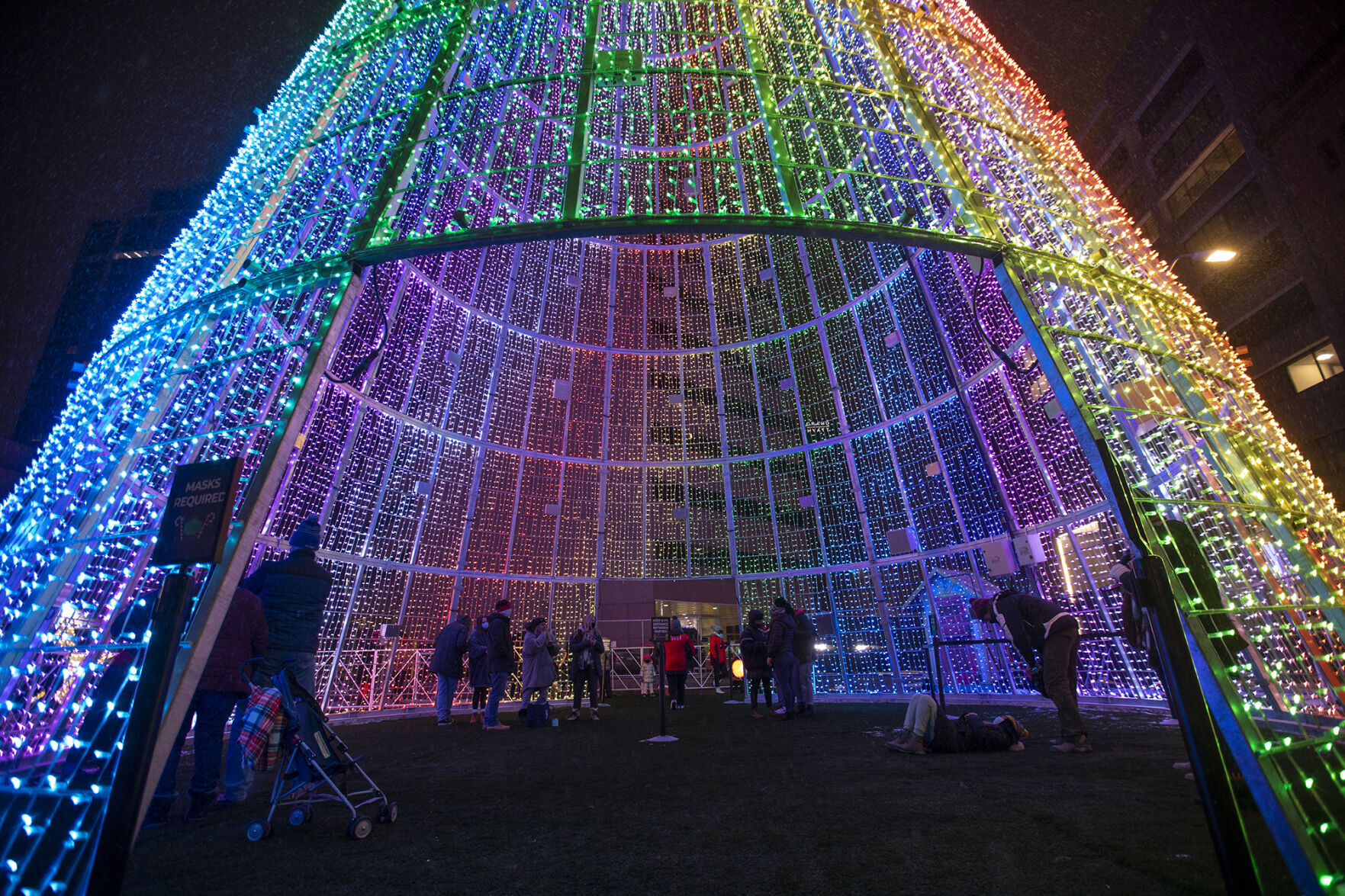 People view the Mile High Tree on Dec. 12, a 110-foot-tall art installation, created by ILMEX Illumination, on 16th Street Mall in Denver. The music and light display lasts around five minutes and will run approximately every 15 minutes. Circles are placed inside the tree in order to ensure social distancing. (Photos by Chancey Bush, The DENVER Gazette)