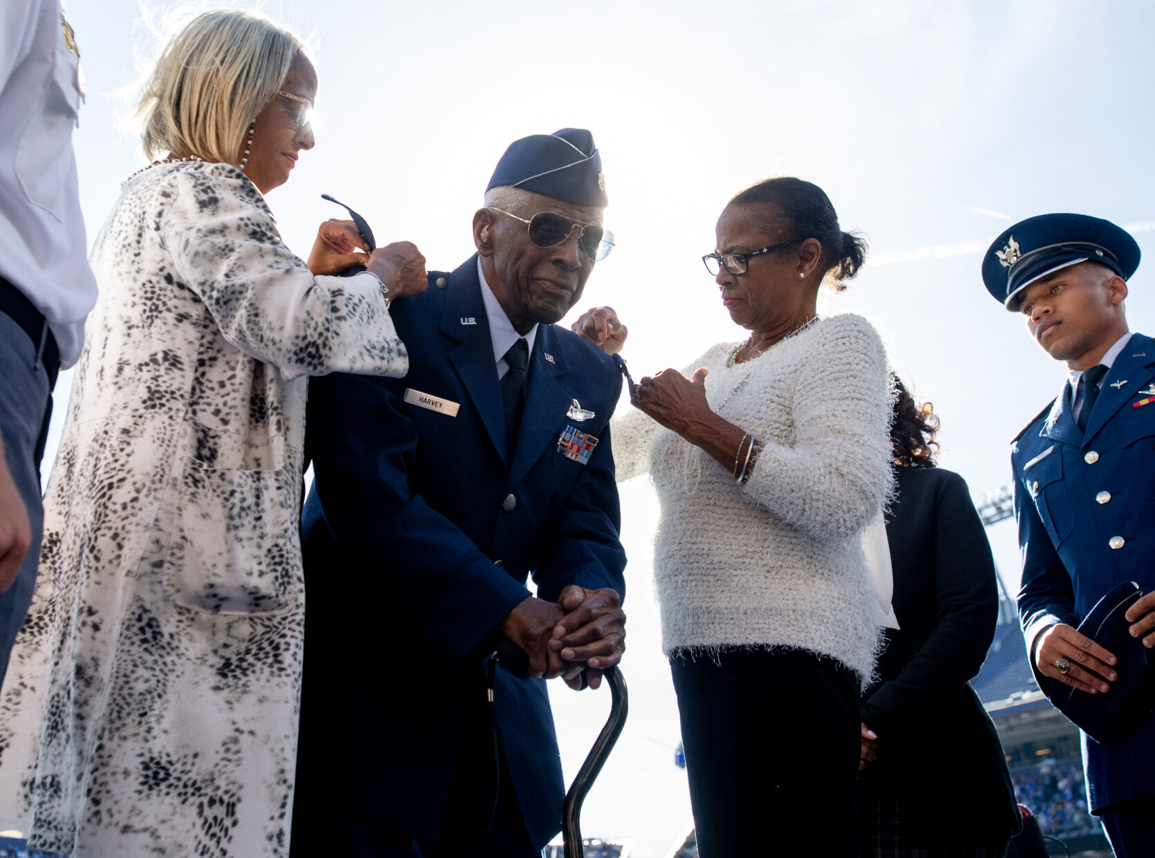 Famed Tuskegee Airman Lt. Col. James Harvey III, center, has silver eagle pins, signifying his honorary promotion to the rank of colonel, pinned to his uniform by his daughters during halftime of the Air Force-Army game on Saturday, Nov. 4, 2023, at Empower Field at Mile High in Denver. (Parker Seibold, the gazette)